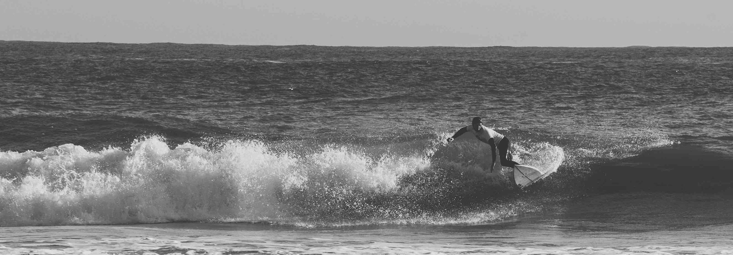 Black and white photo of a surfer riding a wave.