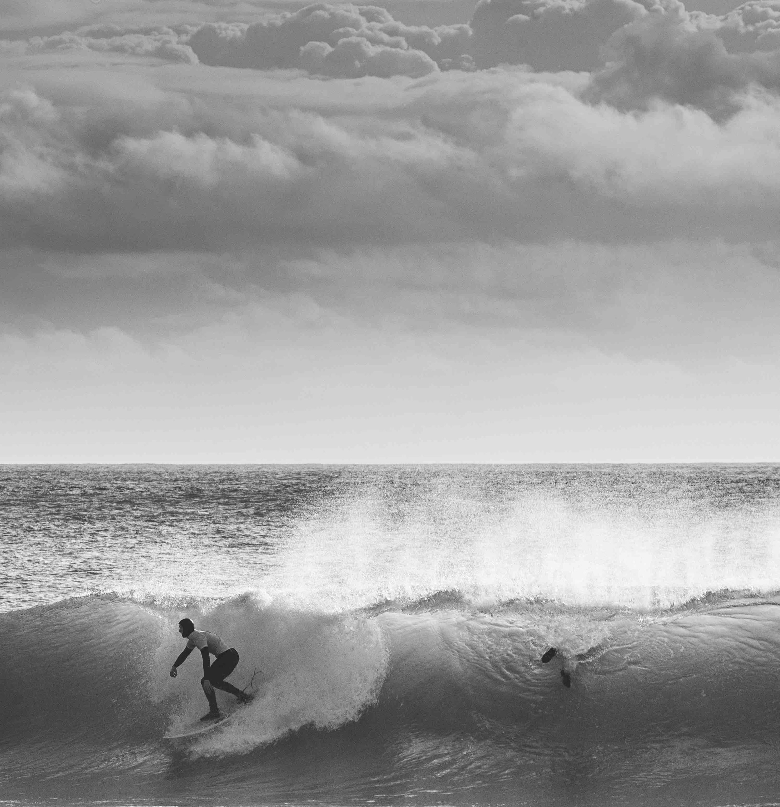 Surfer riding a wave with a cloudy sky above