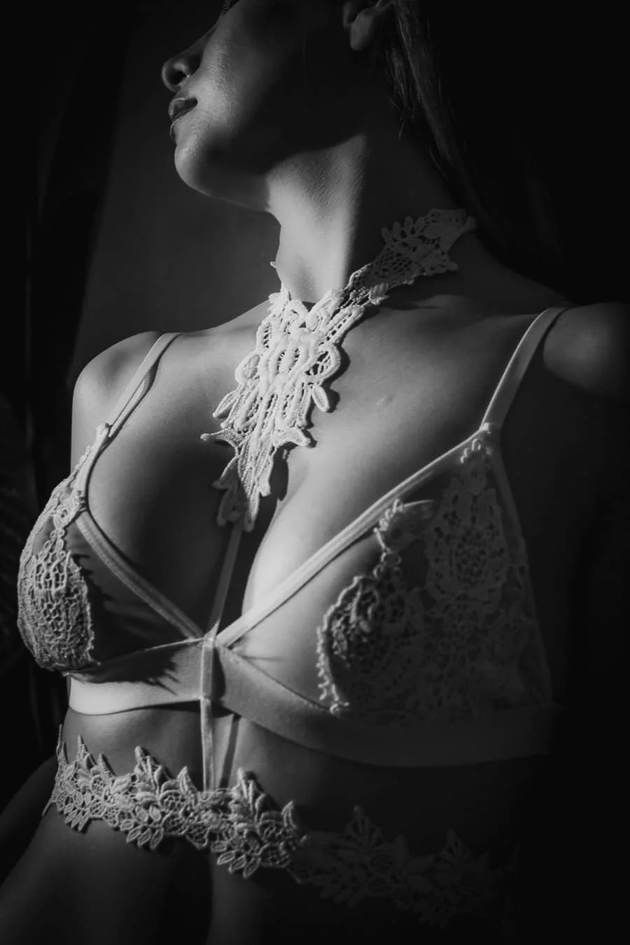 Mujer con ropa interior de encaje y collar de encaje, en luz y sombra en una fotografía en blanco y negro.