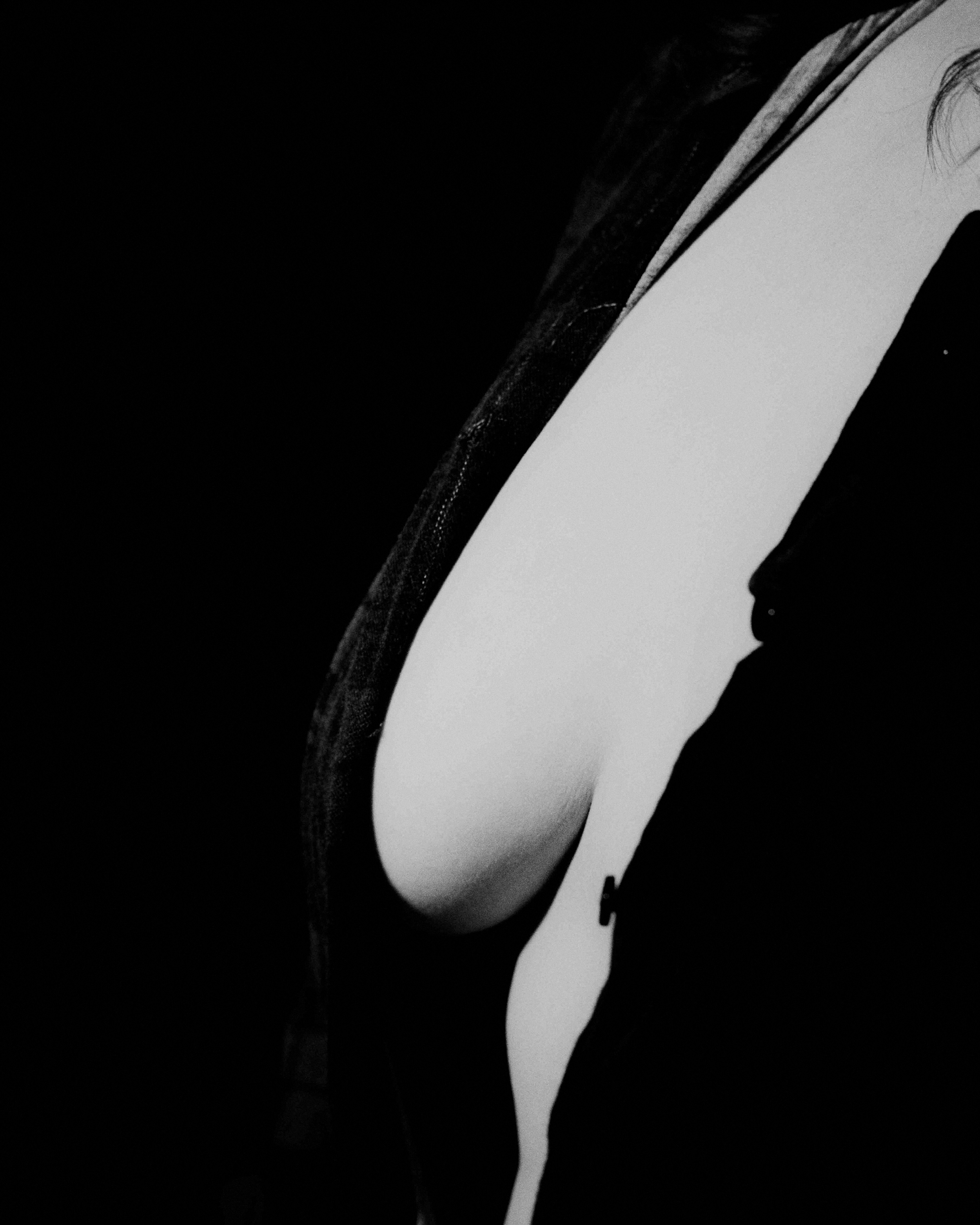 Una mujer usando un vestido negro con un escote que revela parte del pecho, en un entorno oscuro.