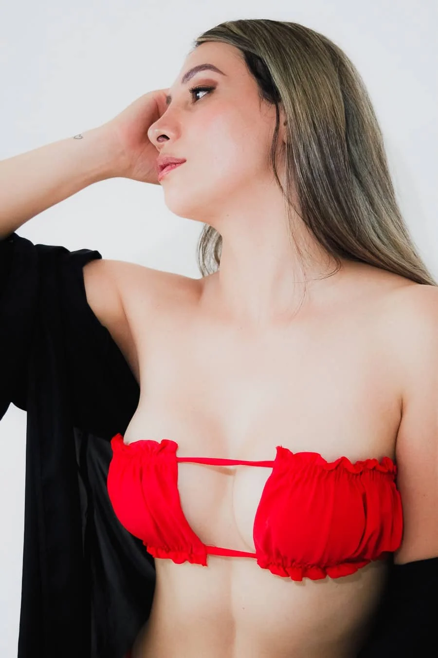 Mujer con peinado largo, sin camiseta, con top rojo y chaqueta negra, mirando hacia un lado.