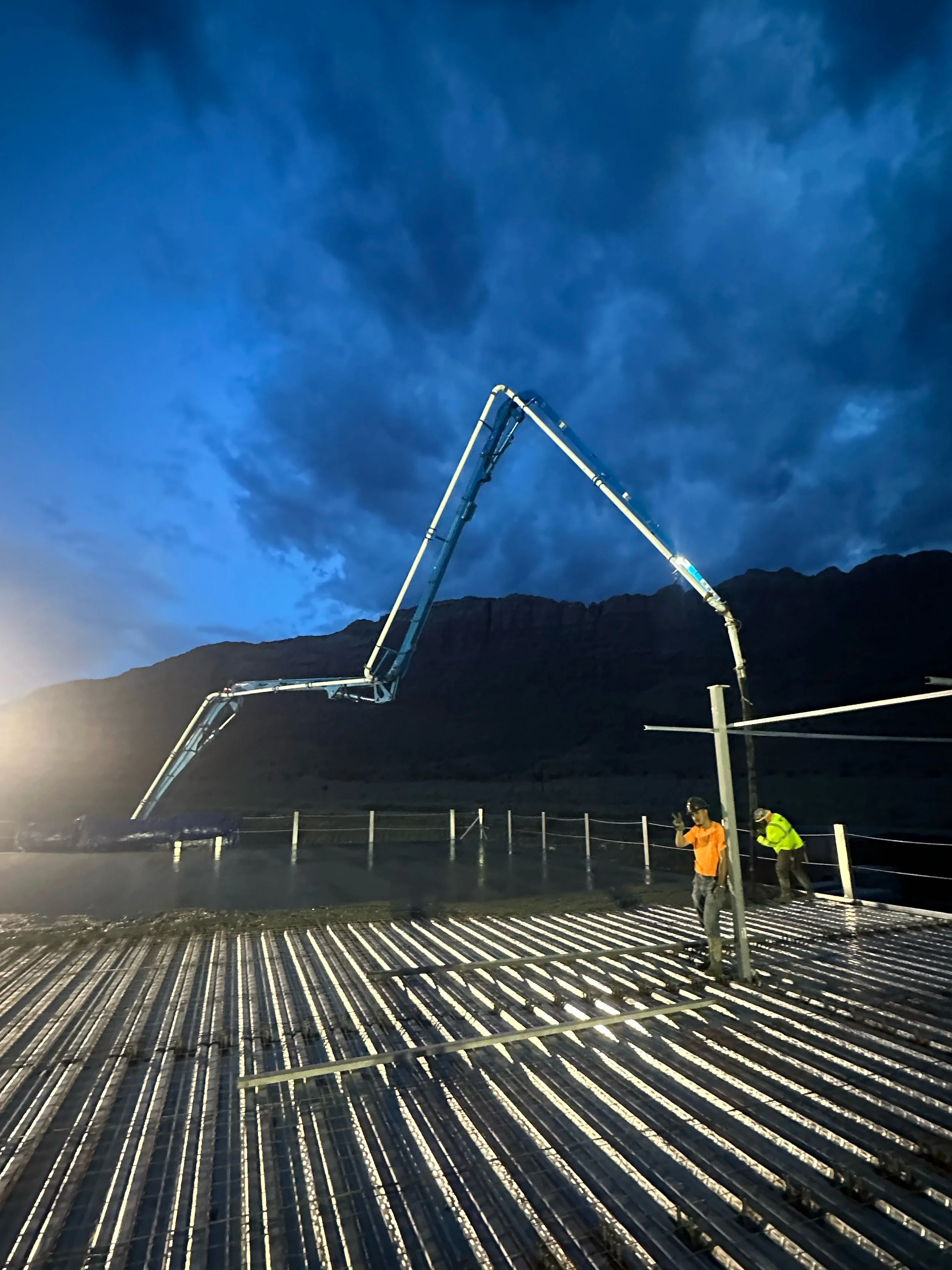Stone Creek Pumping boom pump truck placing concrete at a jobsite in Moab, Utah at dusk.