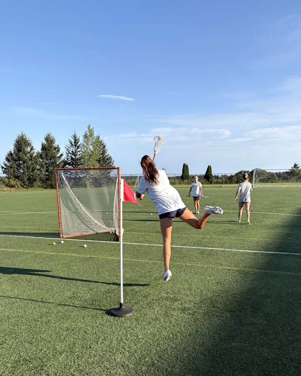 Lacrosse player mid-jump shooting on goal at Big Rock Lacrosse practice field.jpg