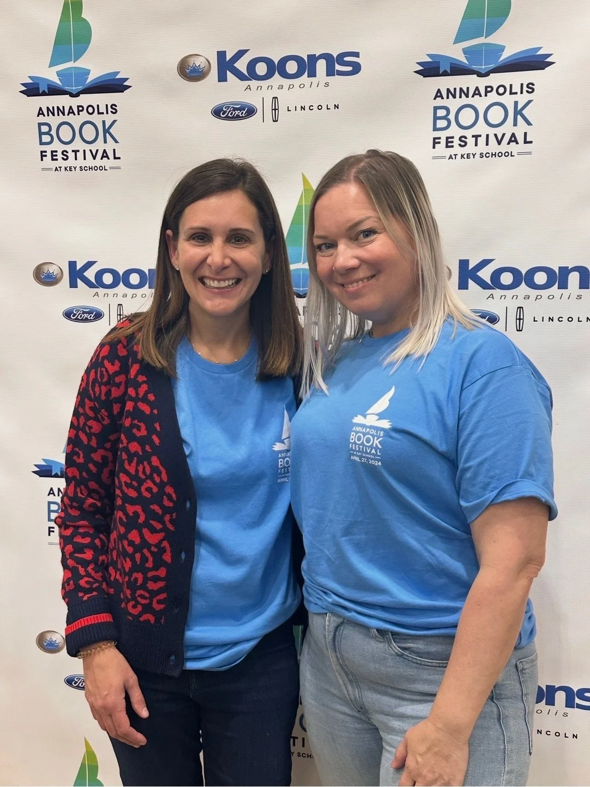 Two women smiling at the Annapolis Book Festival at Key School, wearing matching blue event T-shirts.