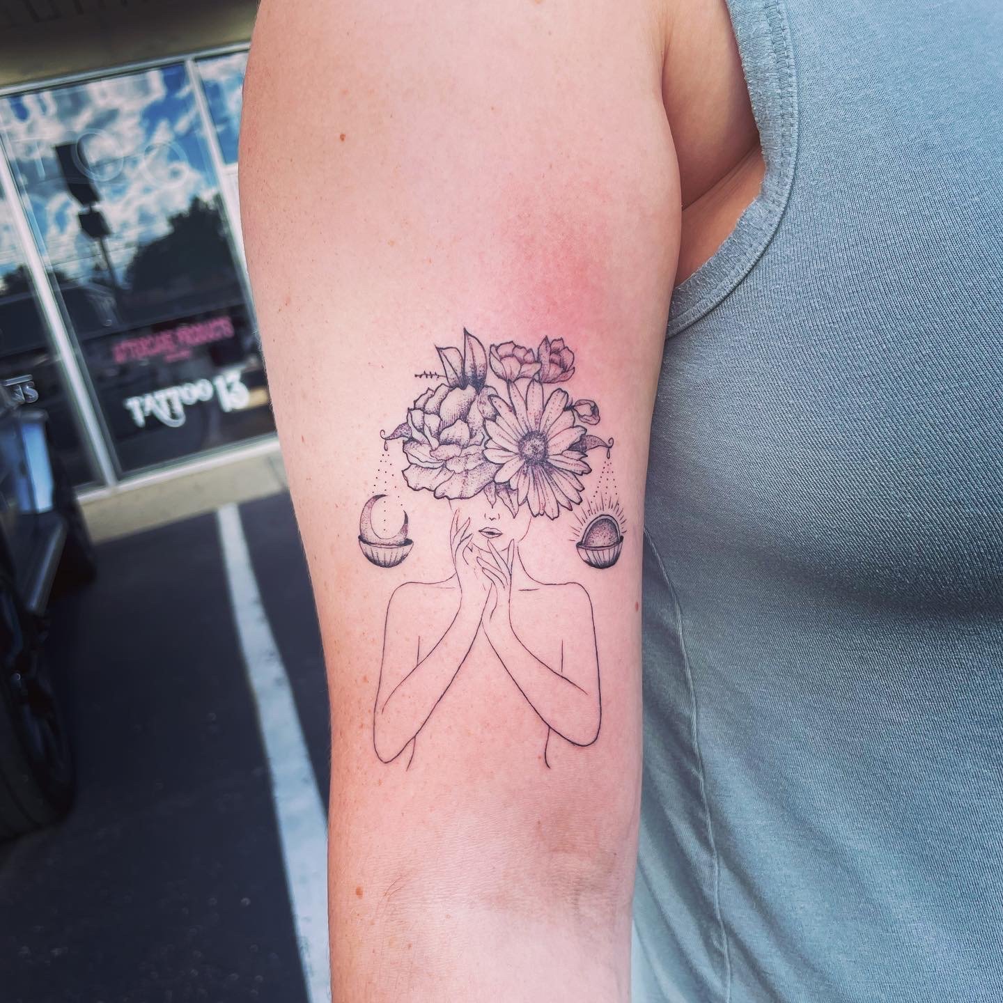 Tattoo of a woman with flowers for a head and celestial elements on arm