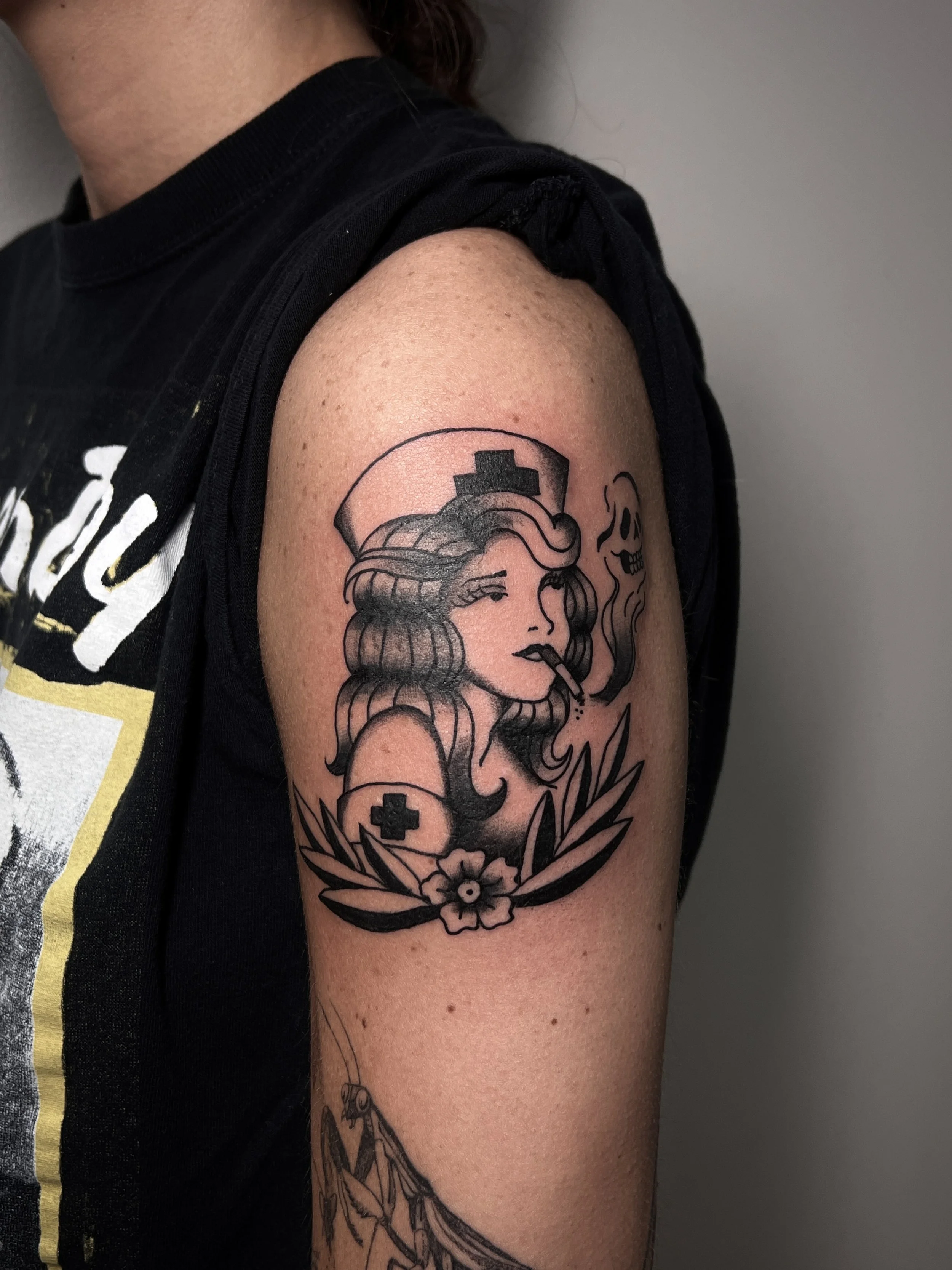 A person's upper arm with a tattoo of a woman wearing a nurse's hat and smoking a cigarette, surrounded by floral and medical symbols.