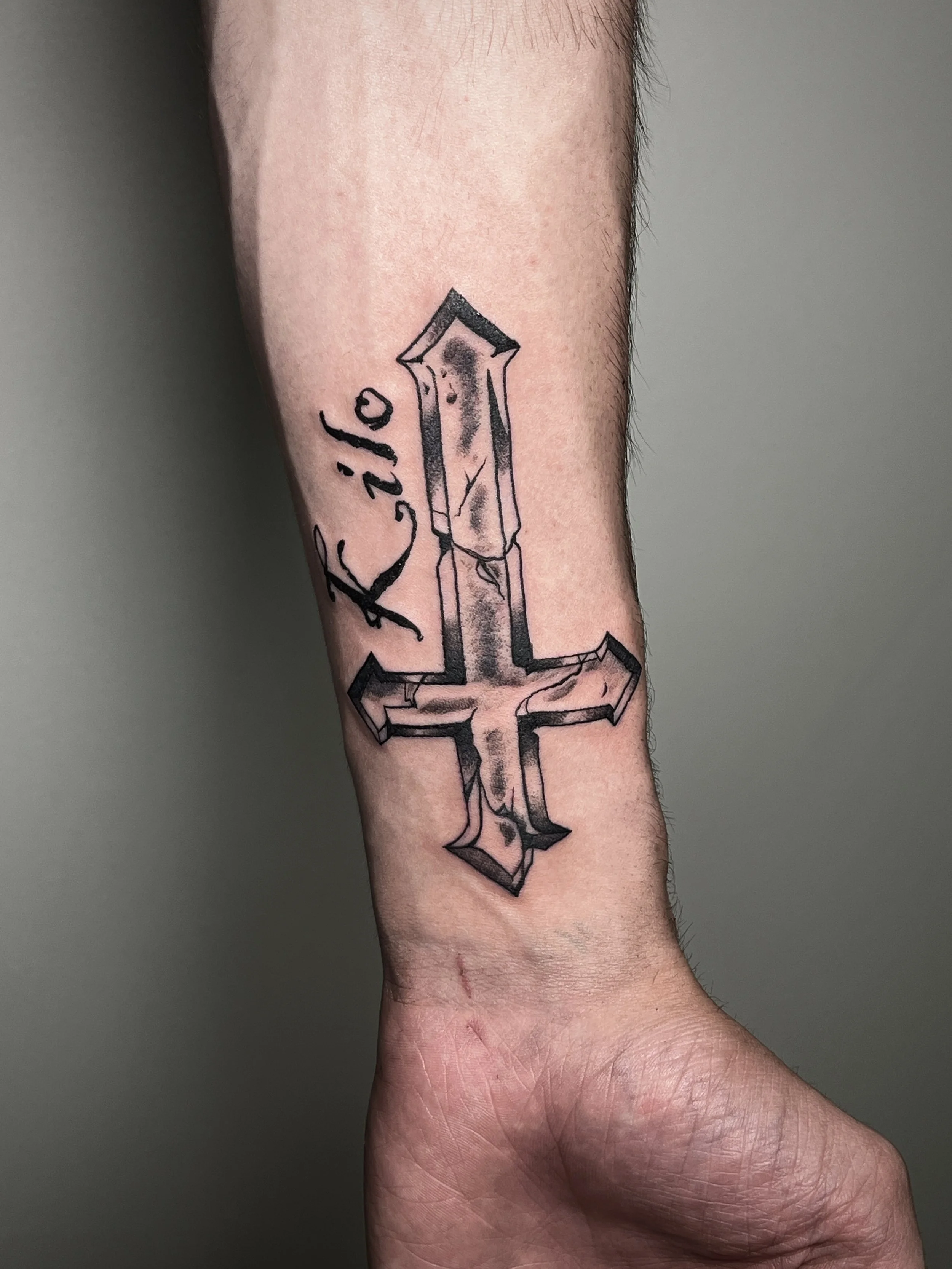 Tattoo of a sword with a cracked cross and the word 'Kilo' on a person's forearm.