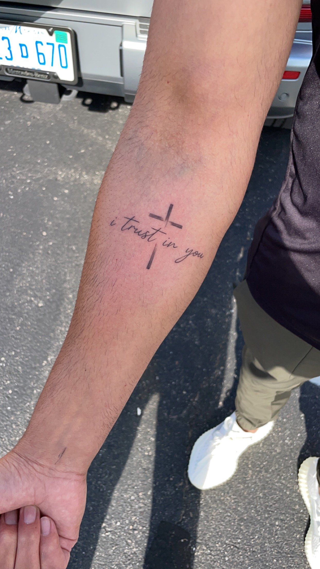Forearm tattoo of a cross and the text "I trust in you."