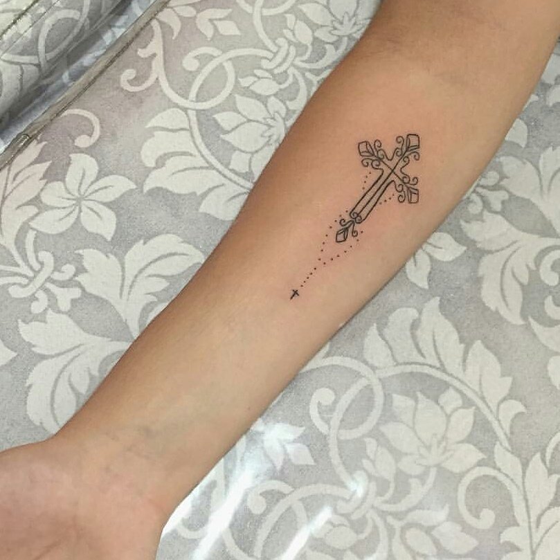 Tattoo of a decorative cross on forearm