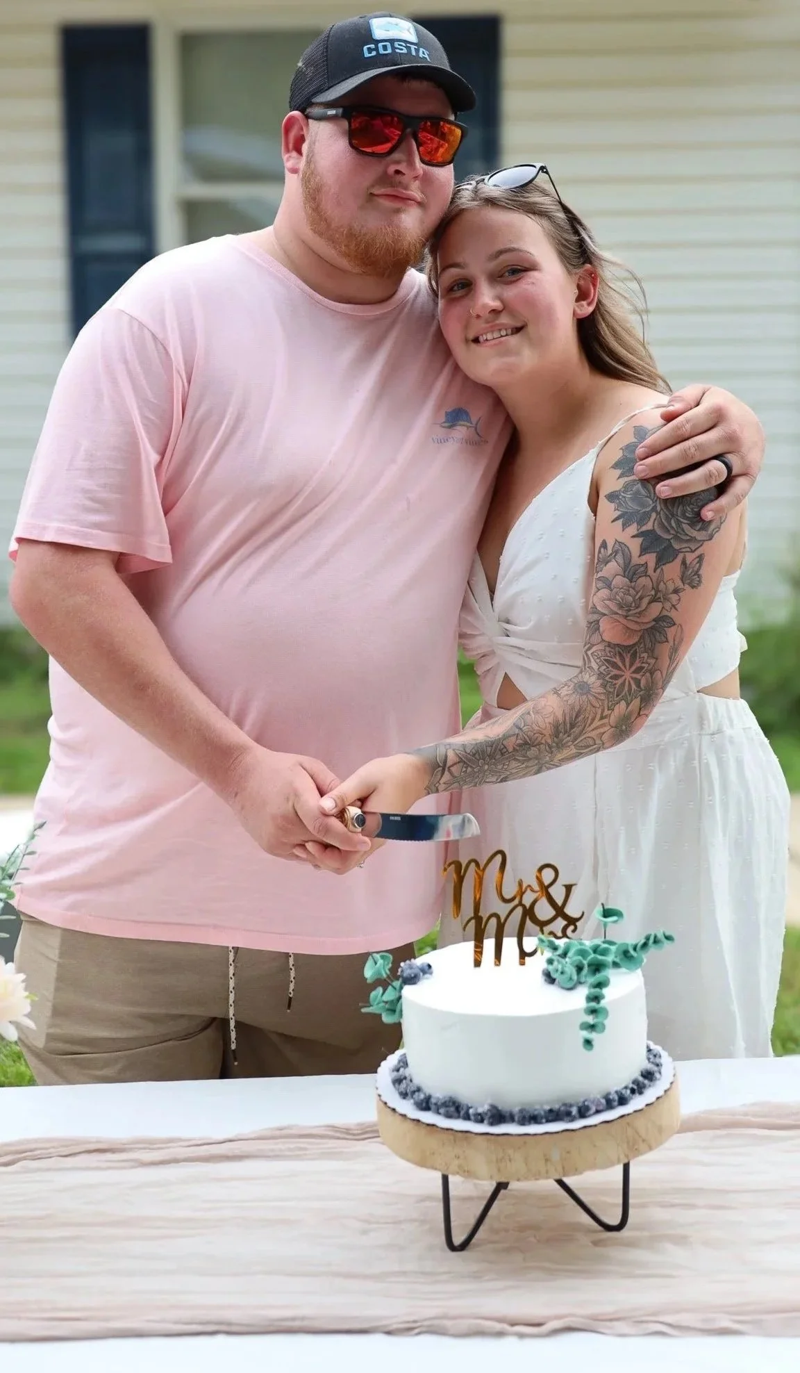 Couple cutting a wedding cake outdoors.