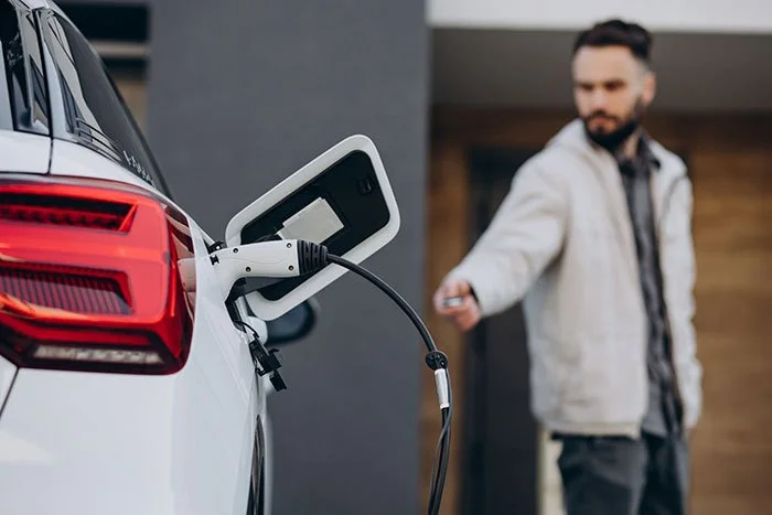 man-charging-electric-car-by-house.jpg