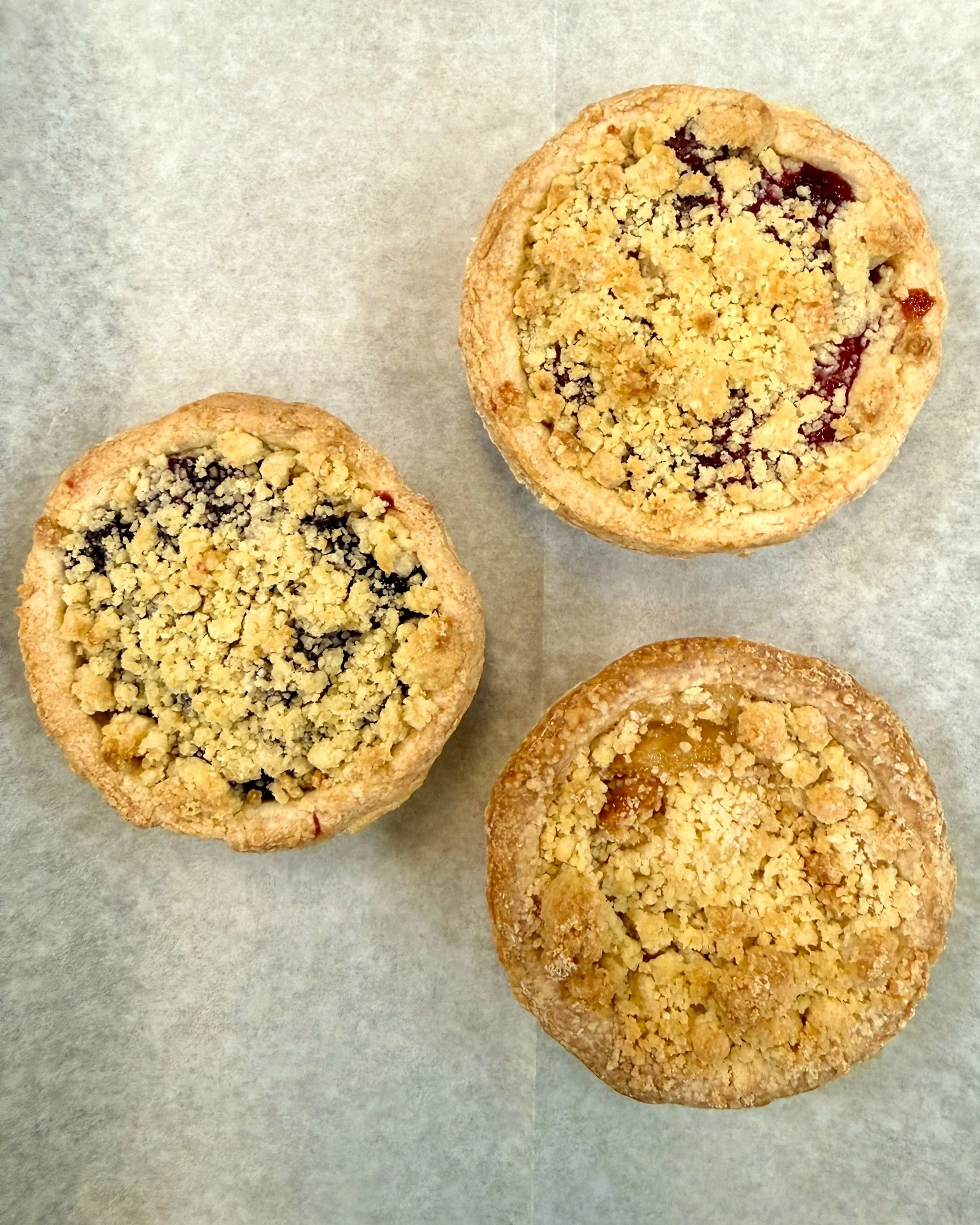 3 inch mini pie featuring apple, cherry, and blueberry filling with a crumb topping