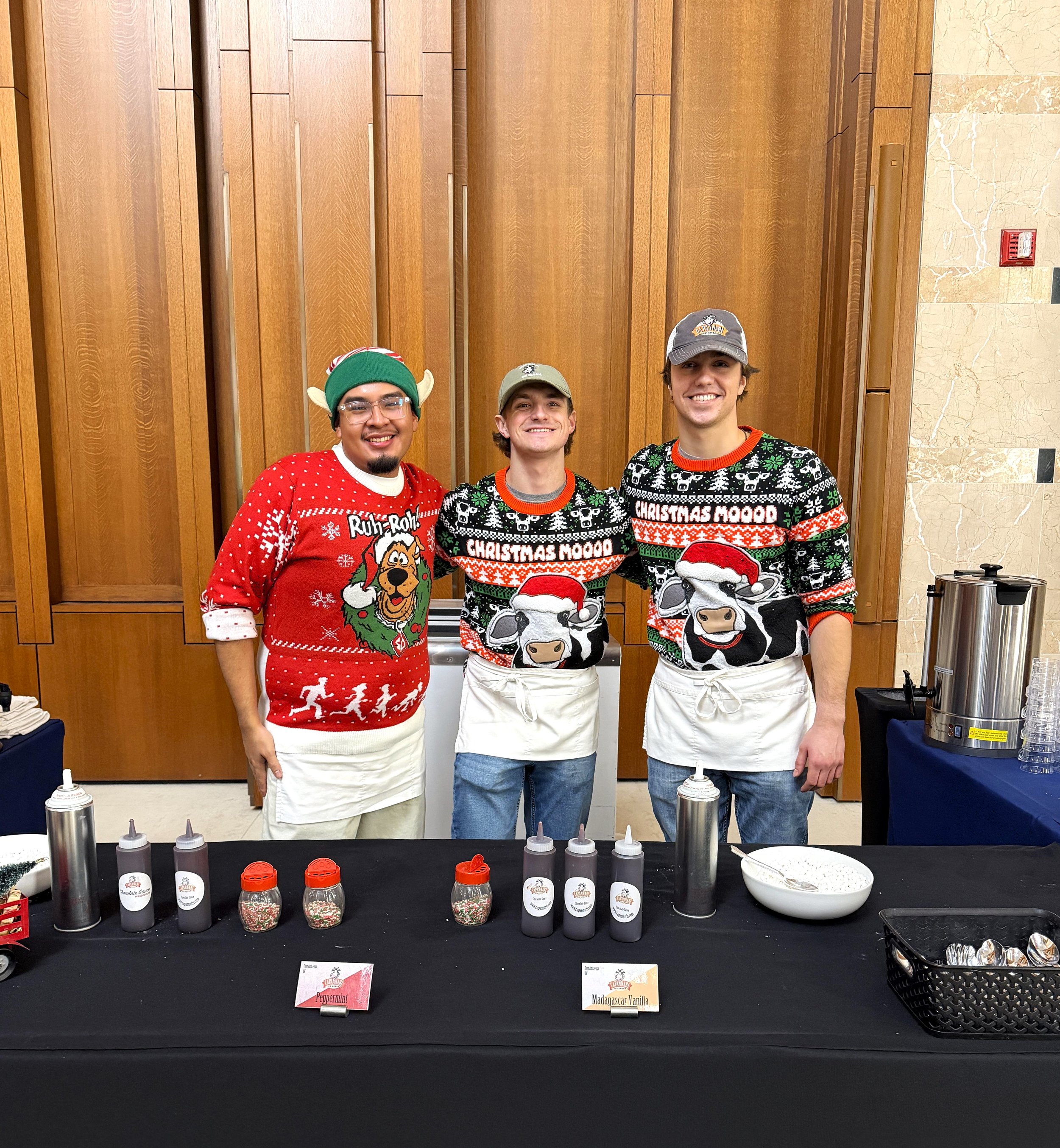 hot chocolate bar with 3 workers wearing holiday sweaters