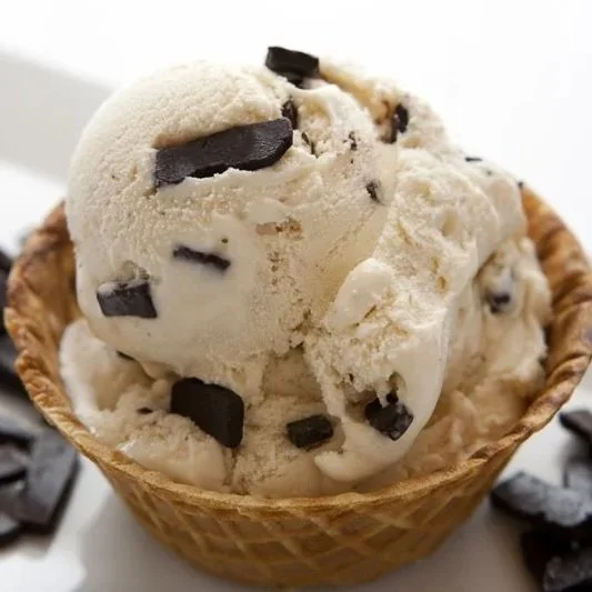 Two scoops of vanilla ice cream with chocolate chunks in a waffle cone