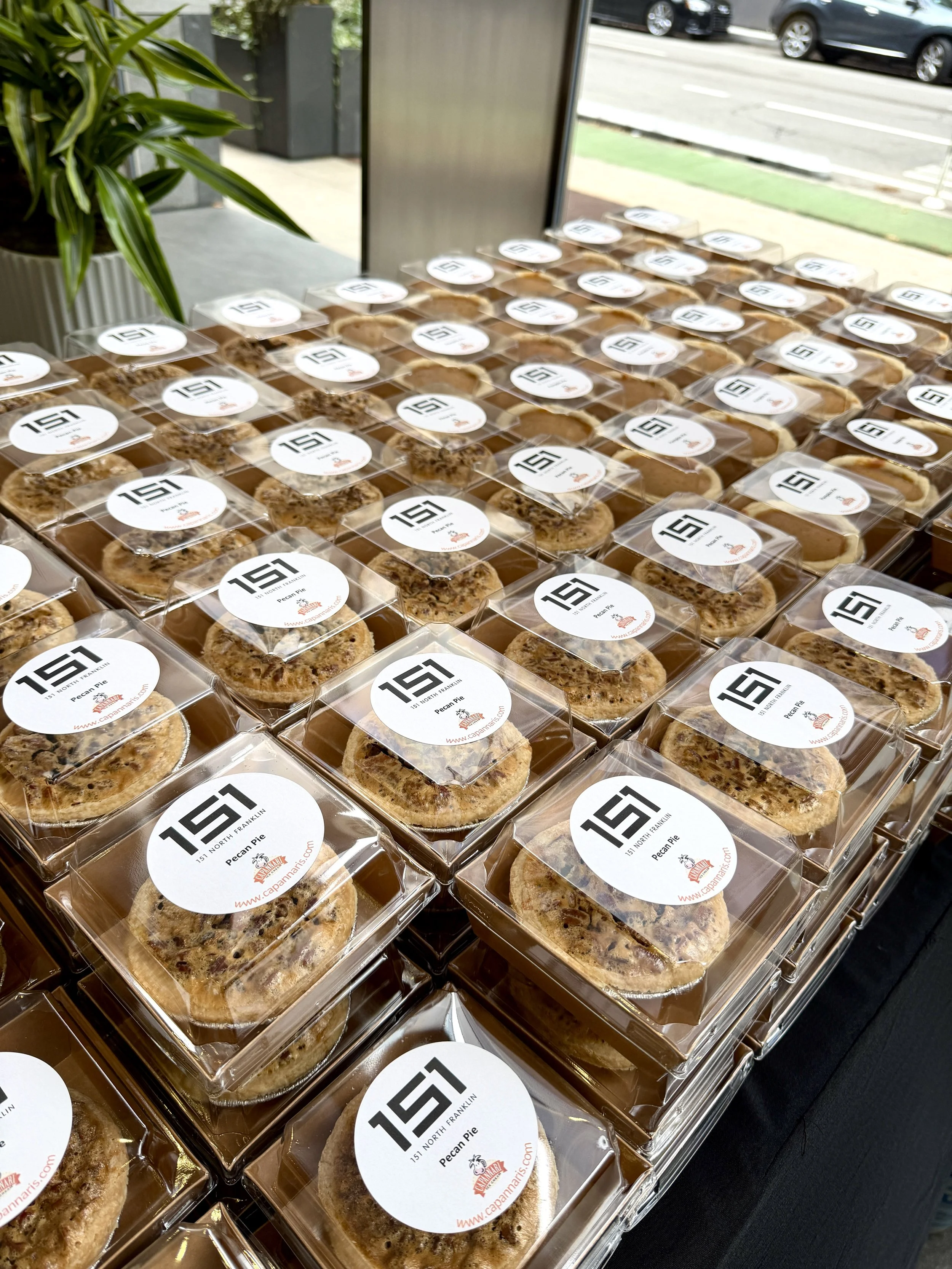 A large stack of individually wrapped and boxed mini pies with customized labels