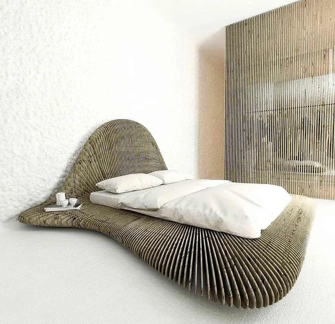 Modern bedroom with a unique, curved bed frame made of dark, slatted material, white bedding, and a small side tray with cups and teapot. A textured white wall is in the background.