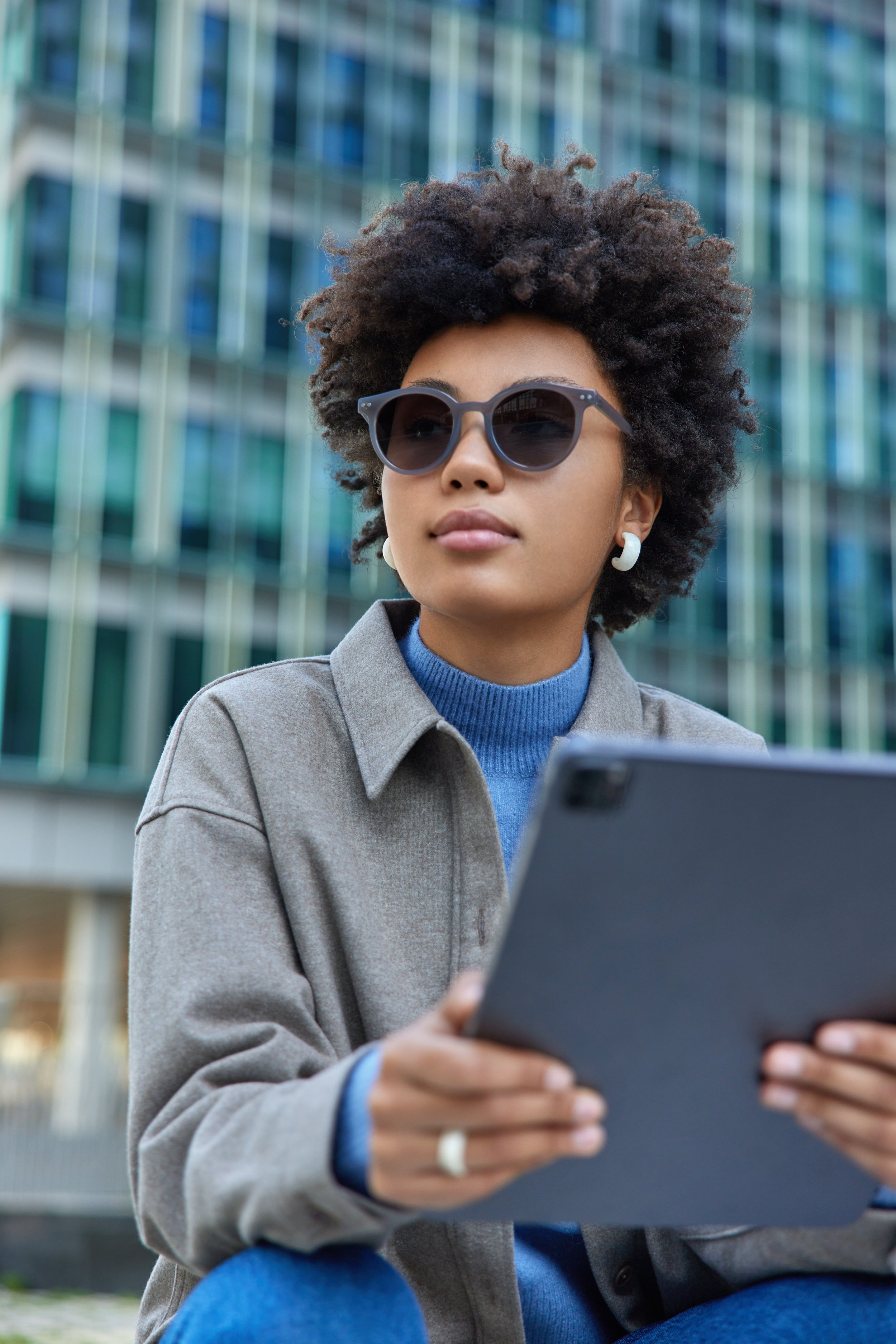 woman-wears-trendy-sunglasses-jacket-holds-modern-digital-tablet-watches-tutorial-video-poses-against-modern-city-building-uses-technology-online-communication.jpg