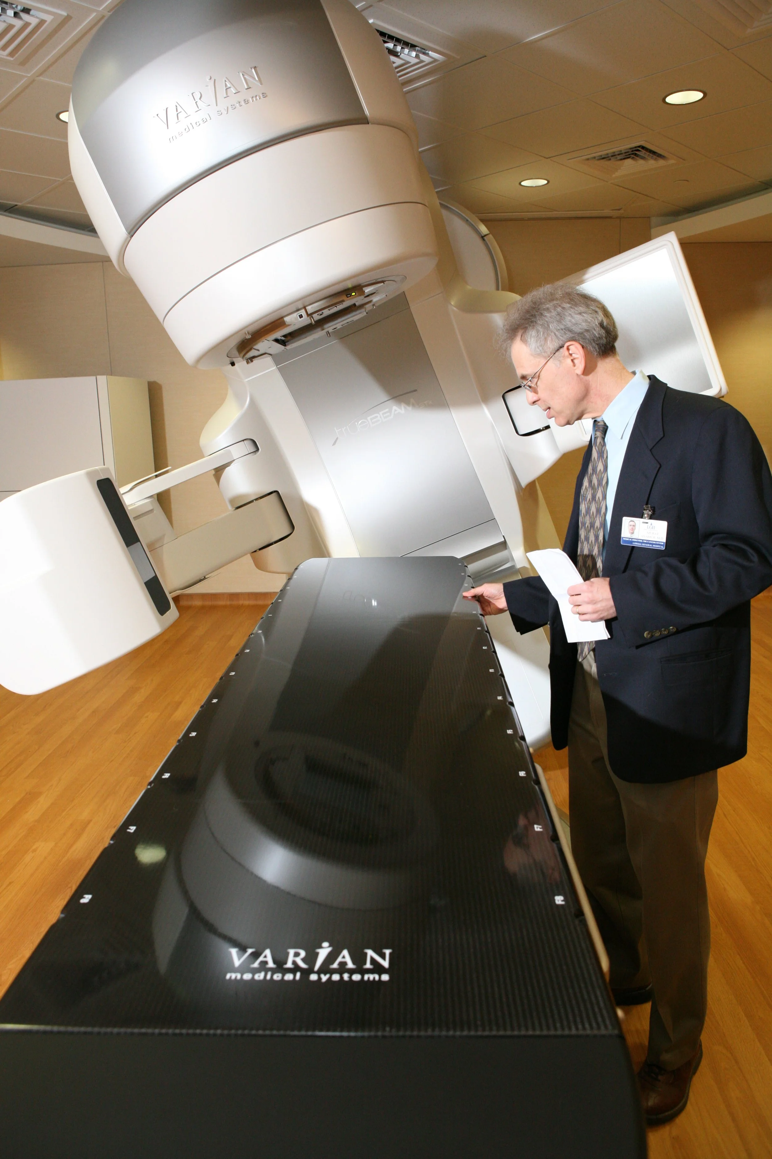 Man examining Varian Medical Systems linear accelerator in a hospital setting.