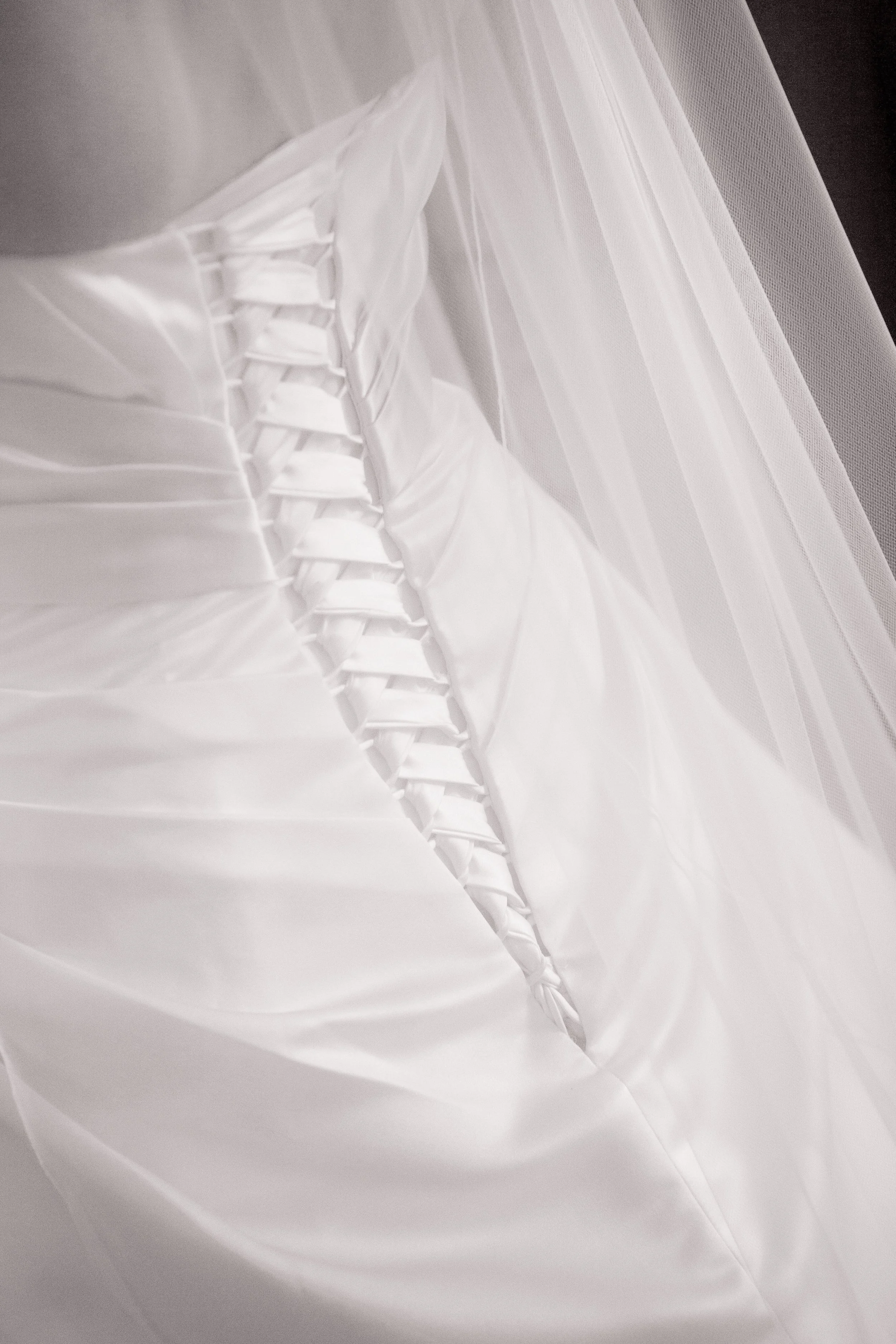 Close-up of a white wedding dress with laced back and sheer veil.