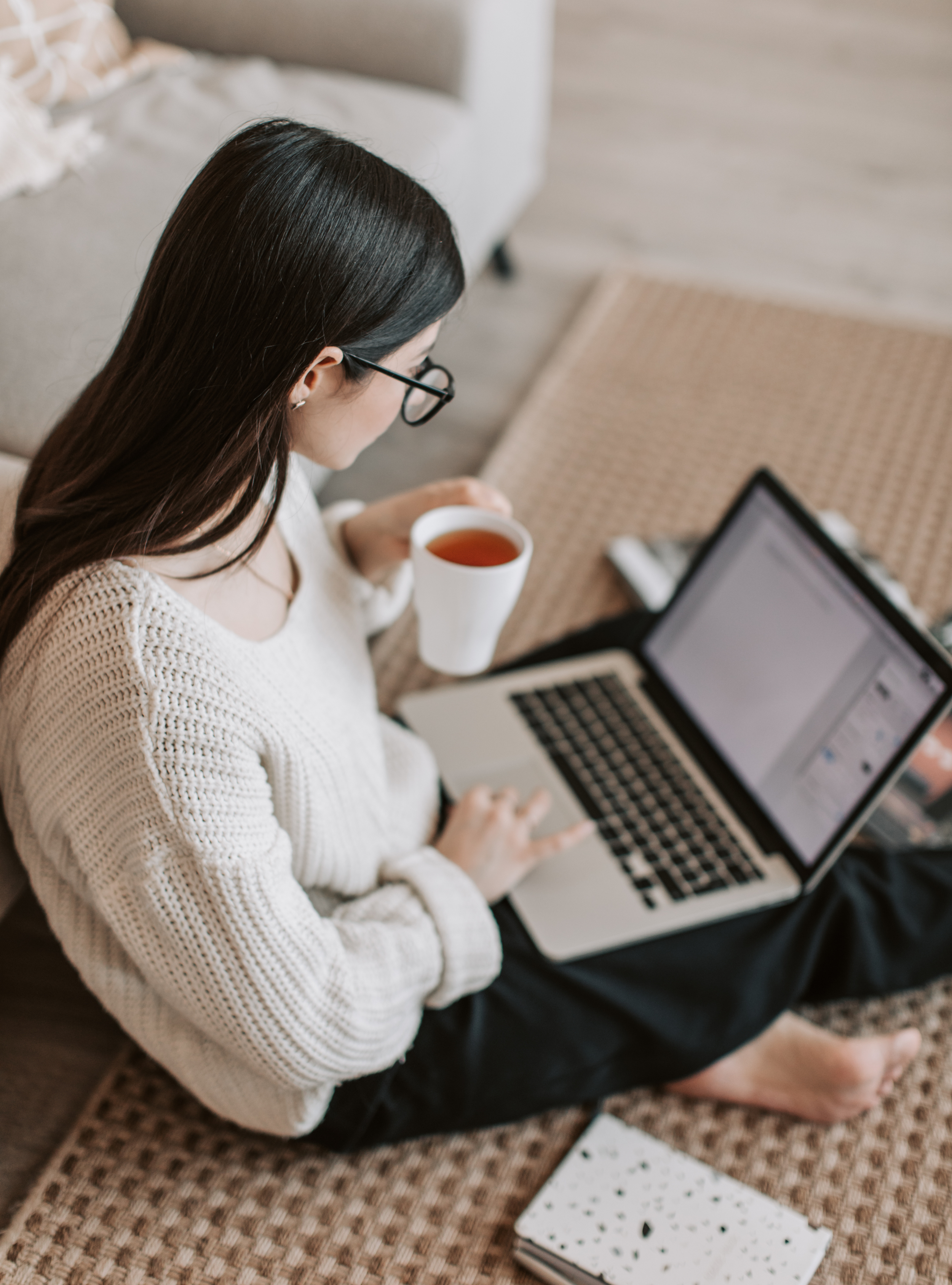 Woman sitting on floor with laptop and tea