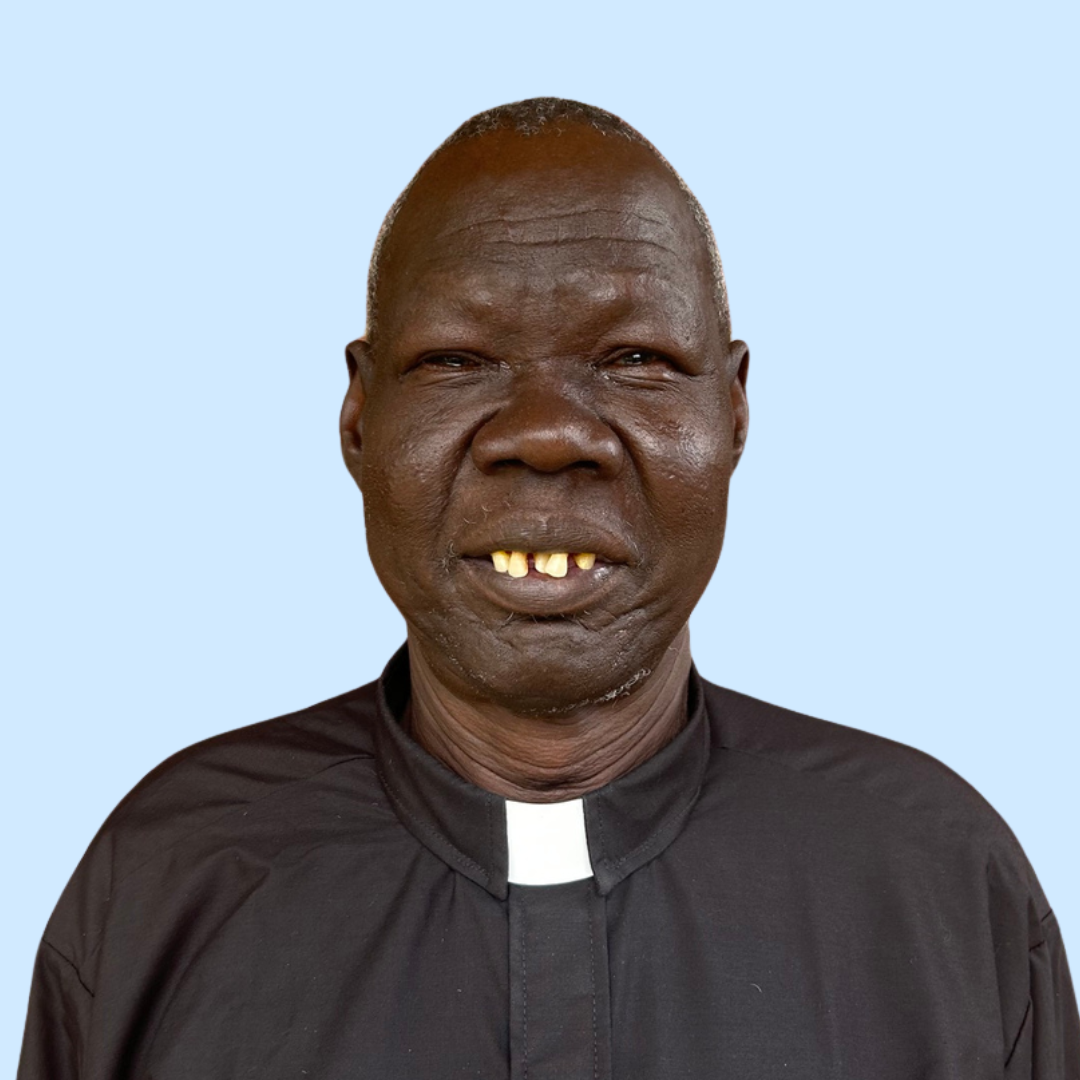 Close-up portrait of an elderly man with dark skin, short gray hair, wearing a beige and blue sweater, with a neutral background.
