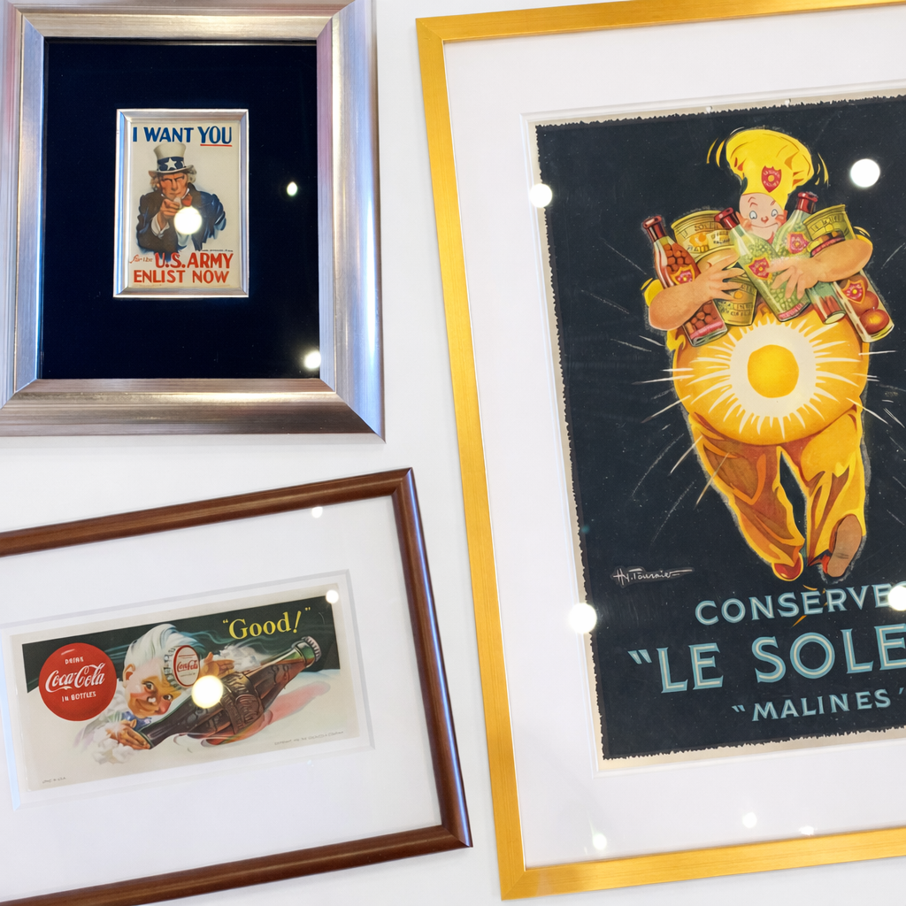 Collection of vintage posters in custom and archival frames, including an American Uncle Sam illustration from World War II, a Coca-Cola advertisement from the 1930s, and a French candy poster from the 1920s.