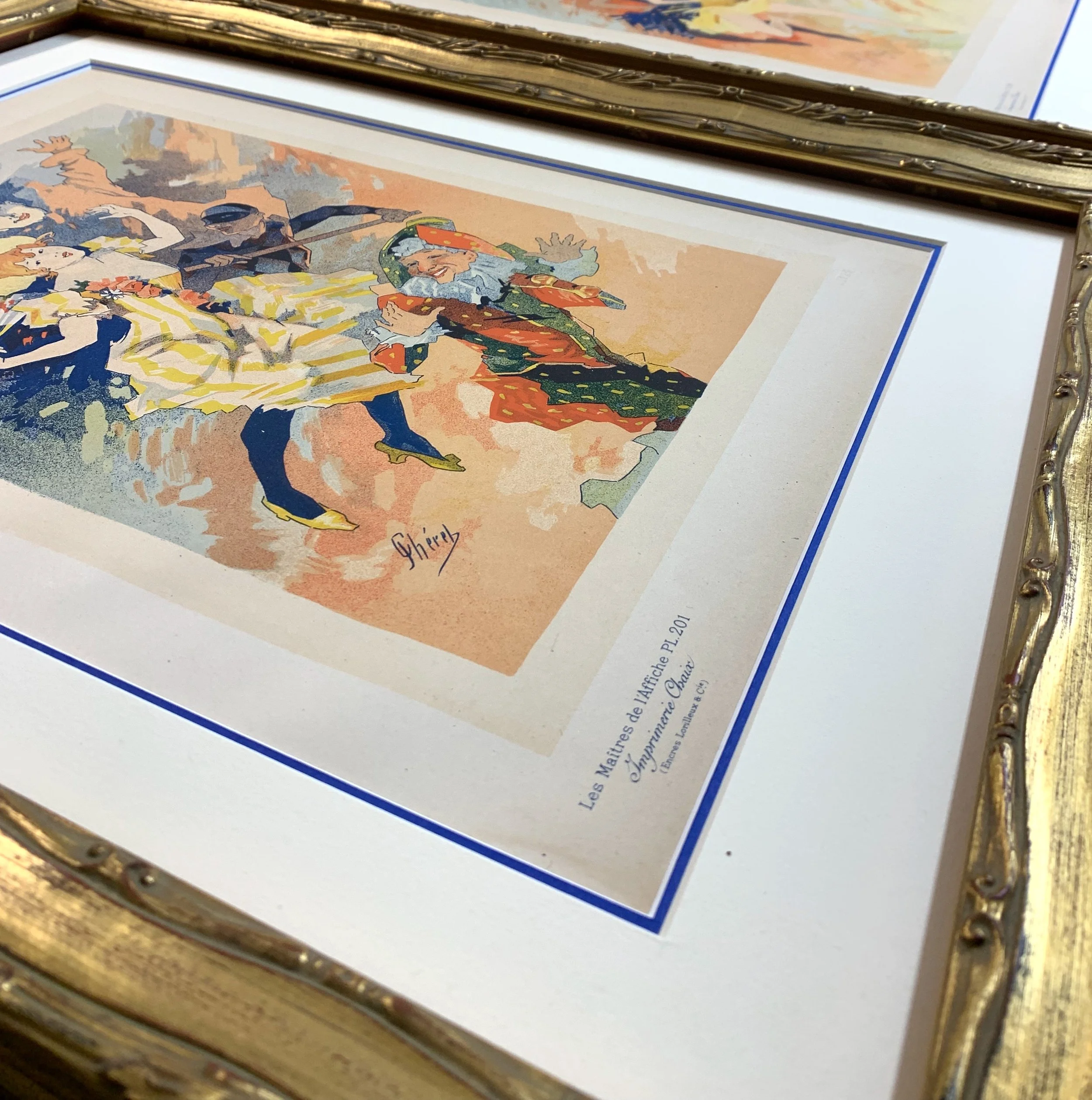 A close up of original 19th century lithographs by Jules Cheret in a "museum package" framing, including archival materials and an ornate hand-gilded frame. 