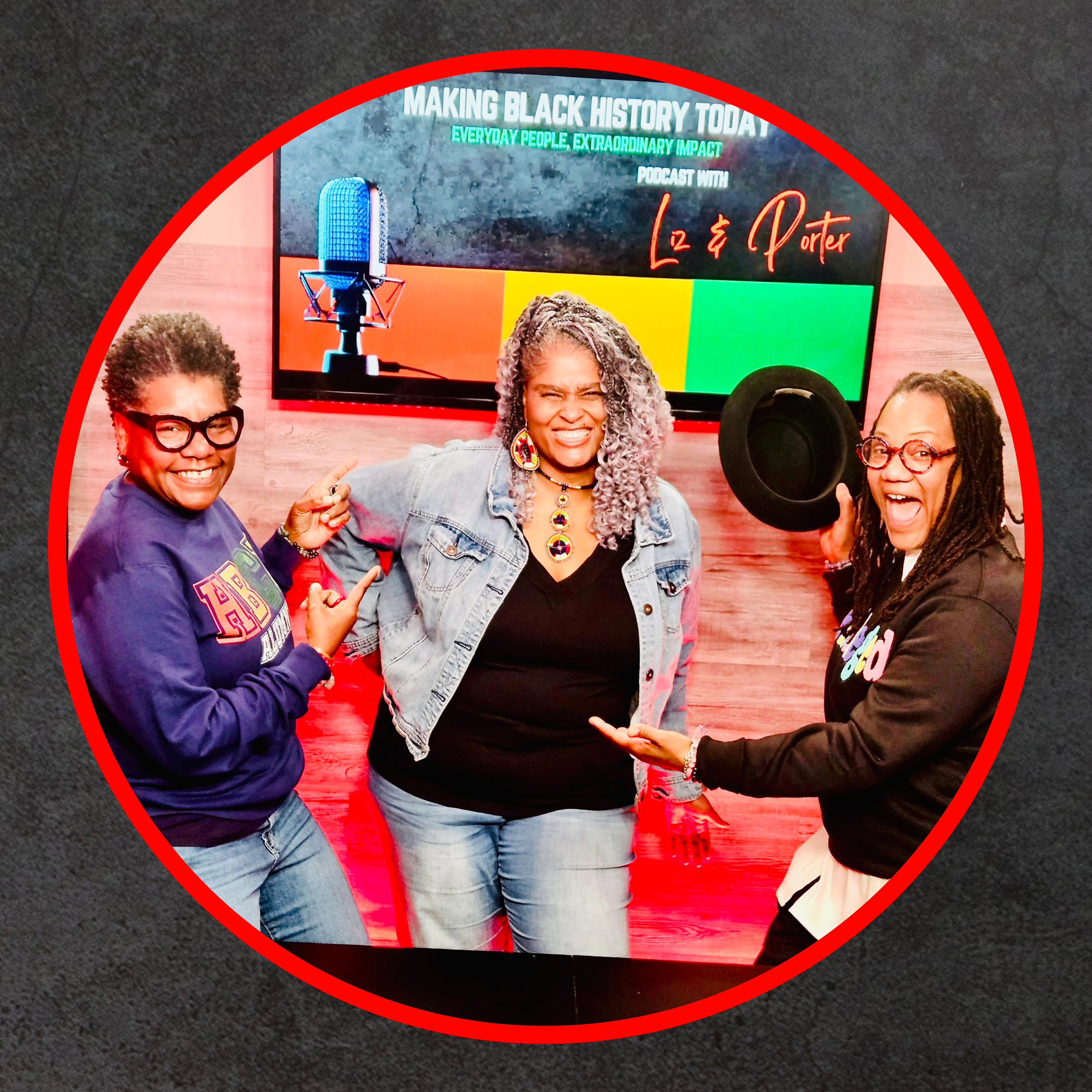 Three women smiling and posing in a studio with a large screen behind them that reads "Making Black History Today" and "Podcast with Liz & Porter". One woman is holding a hat, the other two are pointing at each other.