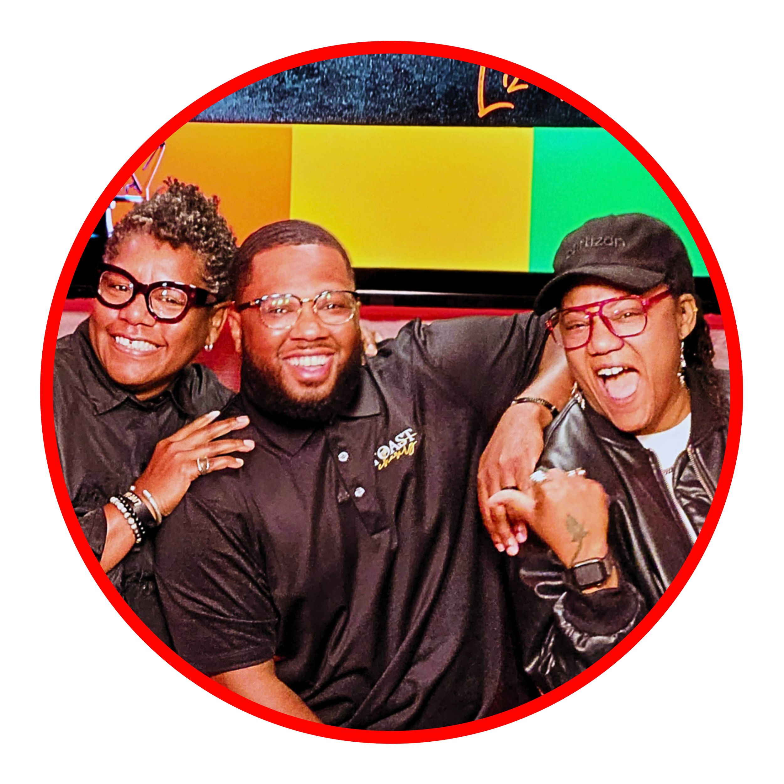 Three people smiling and laughing together inside a colorful setting, wearing casual dark clothing and glasses, with two women on either side and a man in the middle.