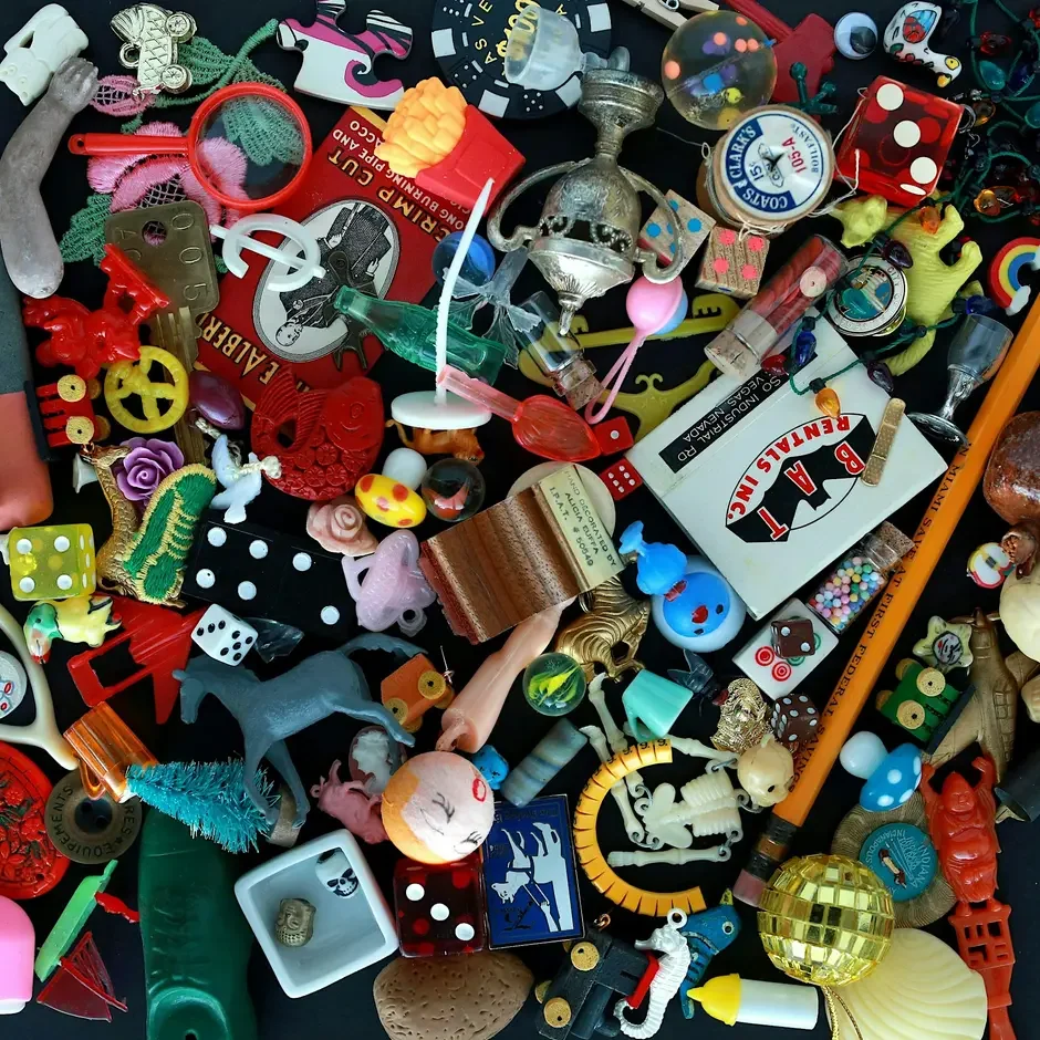 A cluttered collection of small toys, buttons, trinkets, and miscellaneous items scattered across a surface.