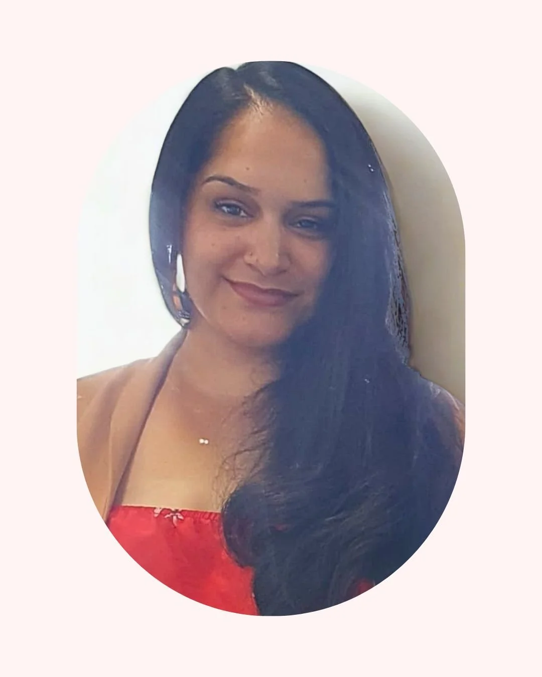 A woman with long dark hair, smiling, wearing a red top with spaghetti straps, in front of a light-colored background. Life Coach Lama client success - Life Coach London - Lama Abou Daher