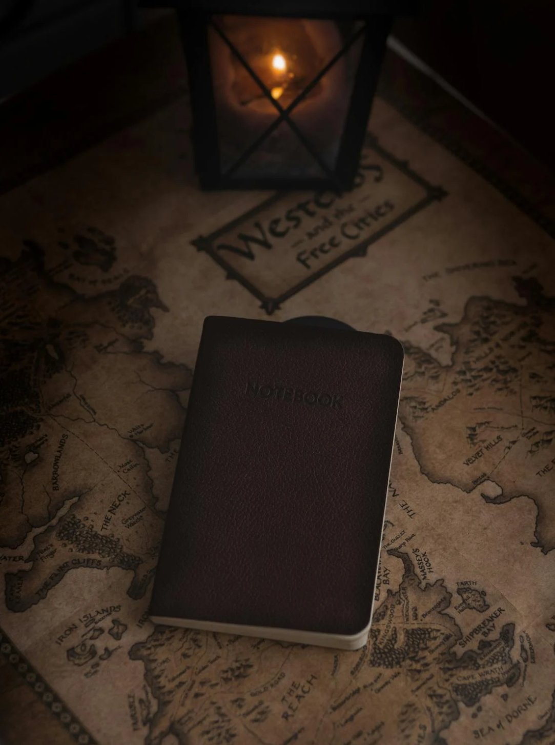 A fantasy map of a world named ‘Westeros’ with a leather-bound book and a candle.