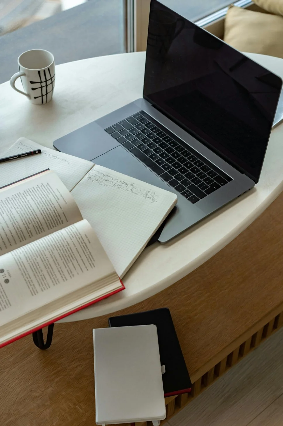 Laptop and handwritten notes on a cosy desk.