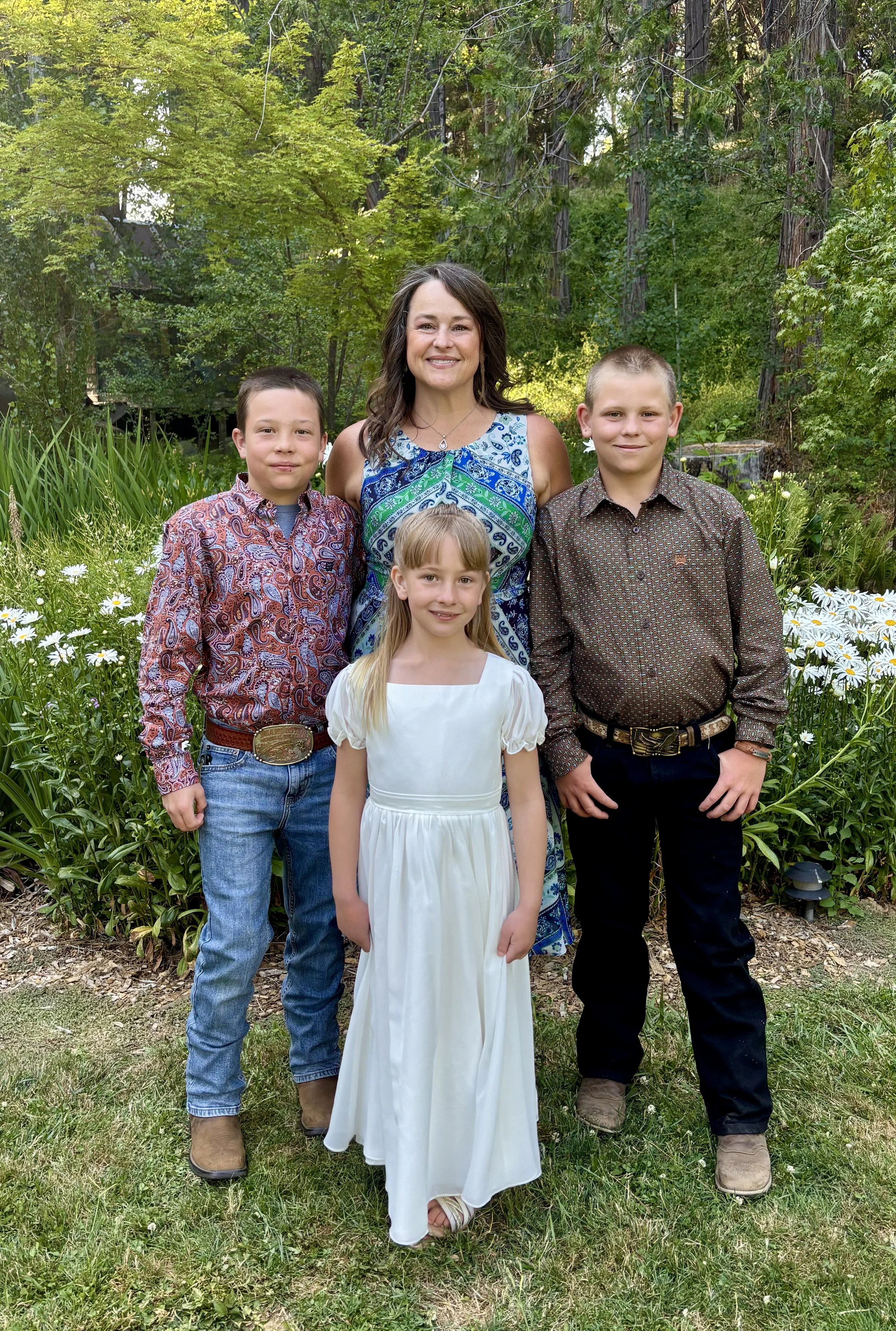 Katie Jaros, she is smiling, with kids, wearing a blue dress, standing in a garden.