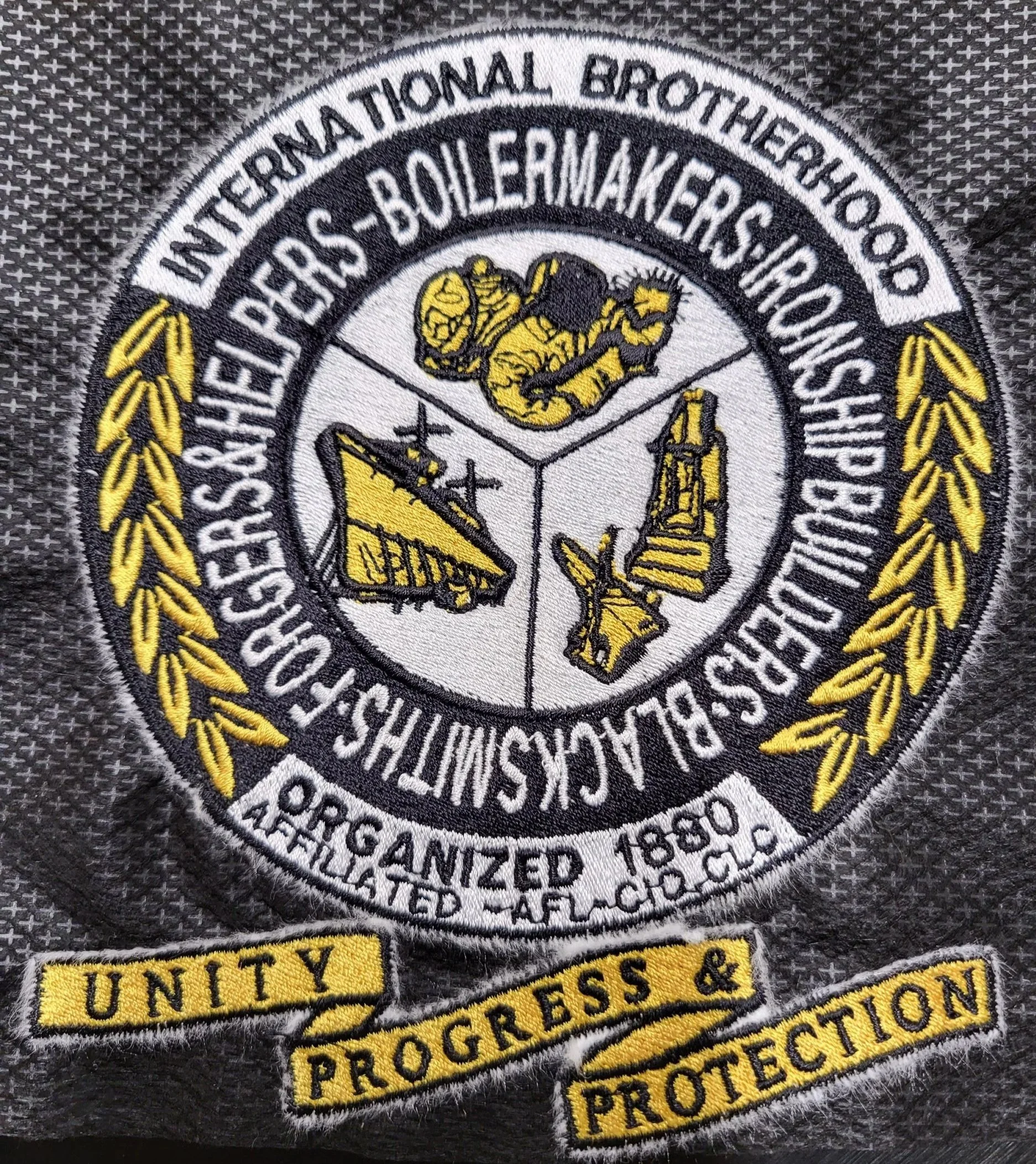 Patch of the International Brotherhood of Boilermakers, with symbols of a hammer, ship, and aircraft, and the words "Unity, Progress & Protection".