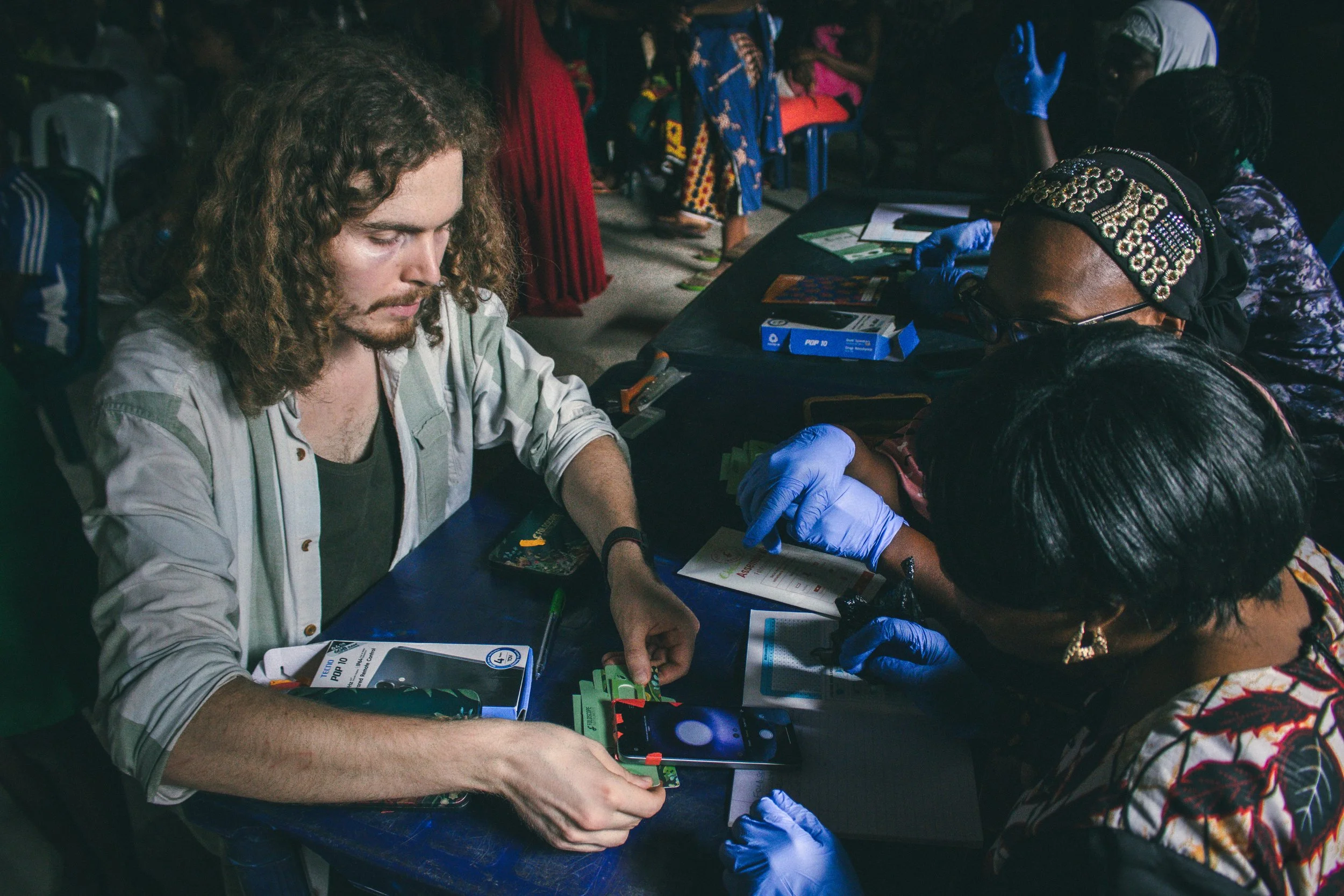 Head of Research William McCarthy training community health workers on schistosomiasis detection with the Foldscope and a smartphone
