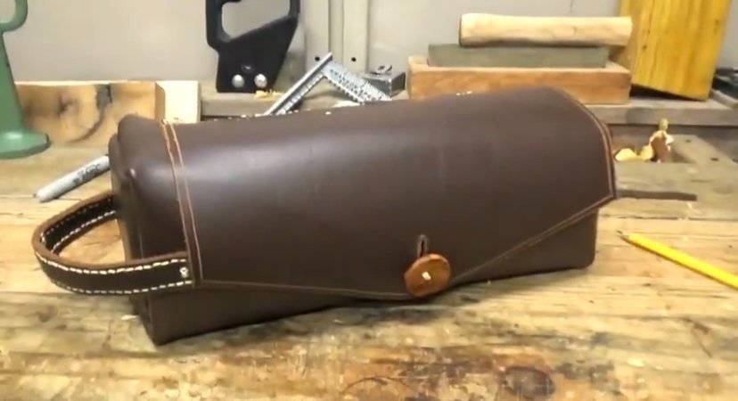 A small leather toiletry bag with a wooden button.