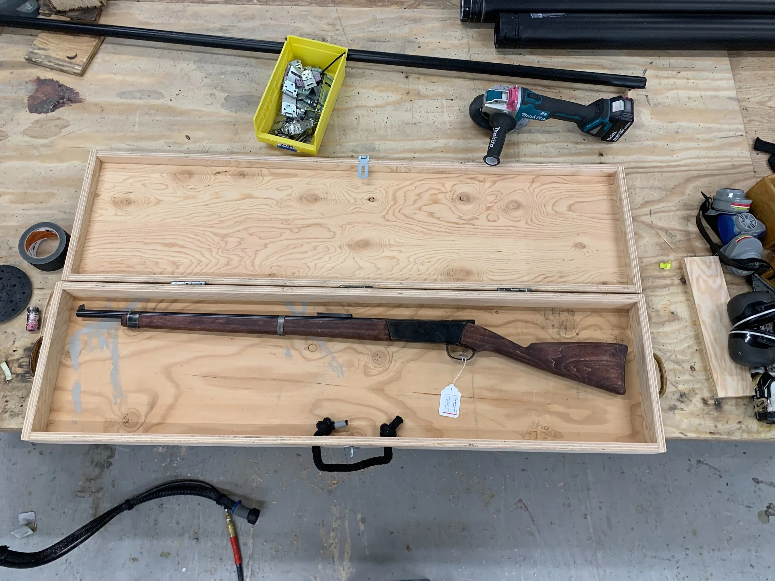A carrying case for transporting and storing two prop rifles between rehearsals and performances. A latch allows the case to receive a lock and foam was later added in each half to secure the firearms within the case (The Santa Fe Opera).