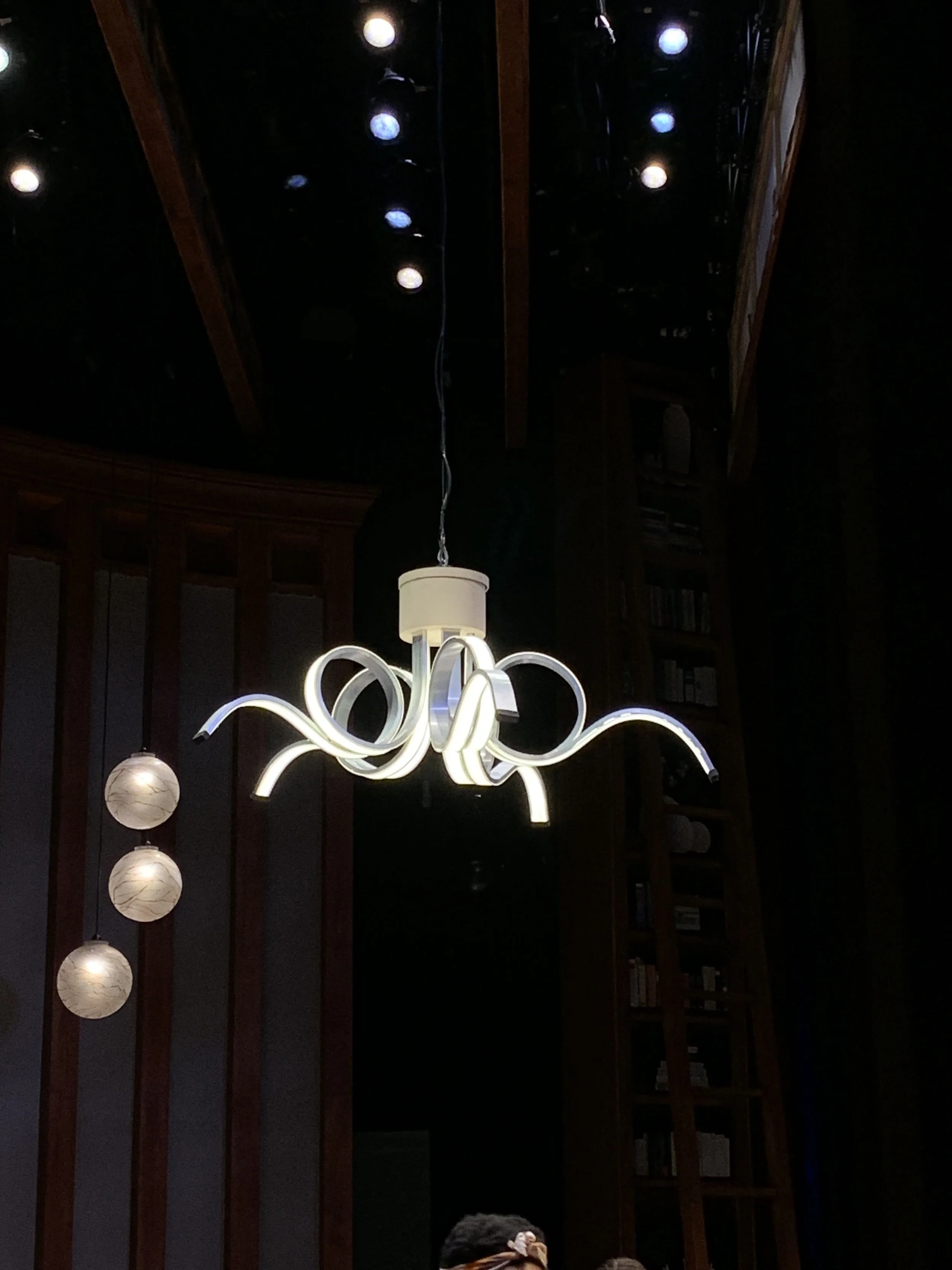 A modern chandelier made from aluminum, steel, plastic, and wood. Wired and illuminated by The Clarice technology shop.