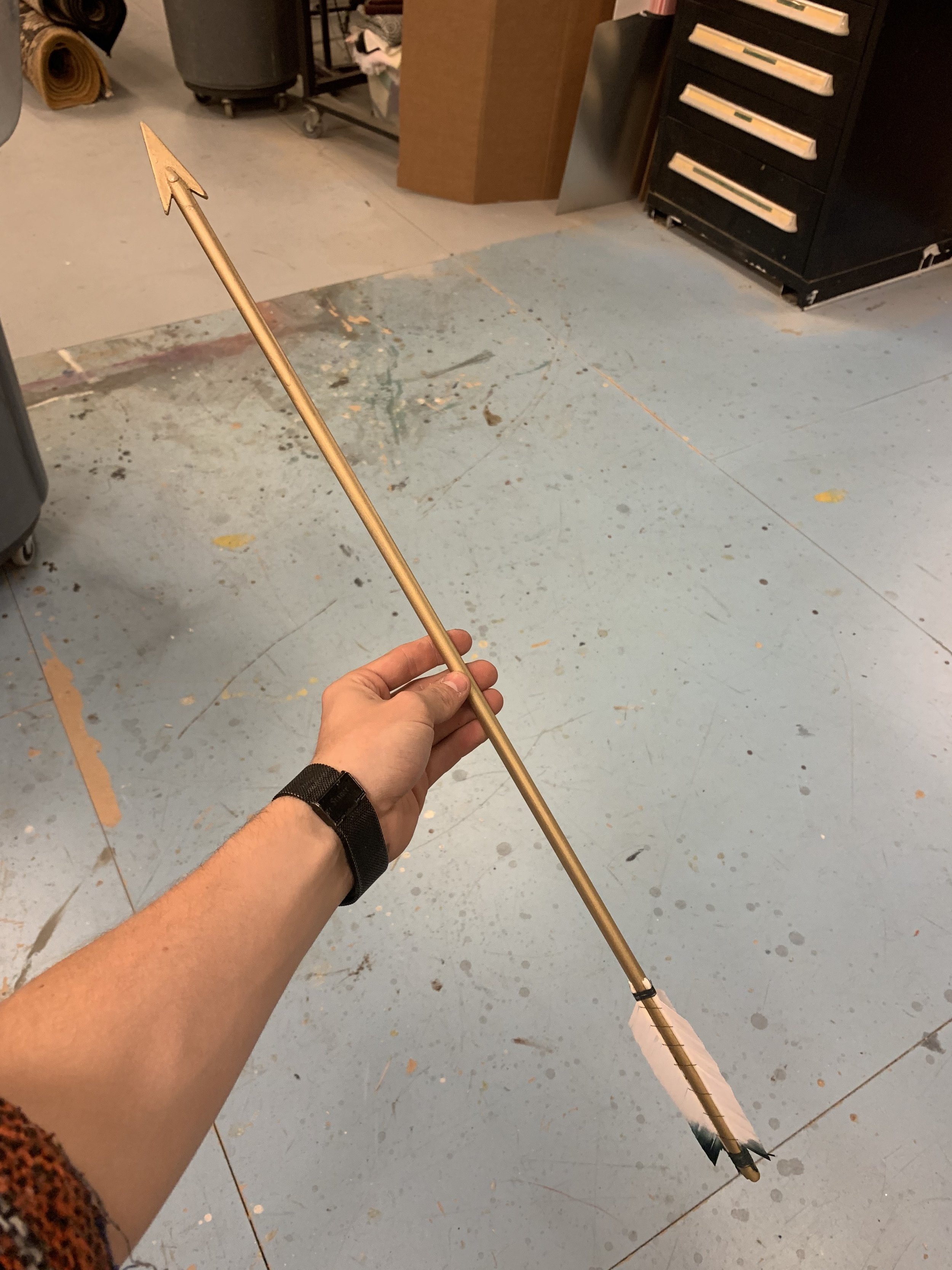 A golden arrow made out of aluminum and feathers for a production of Metamorphoses (UMD)