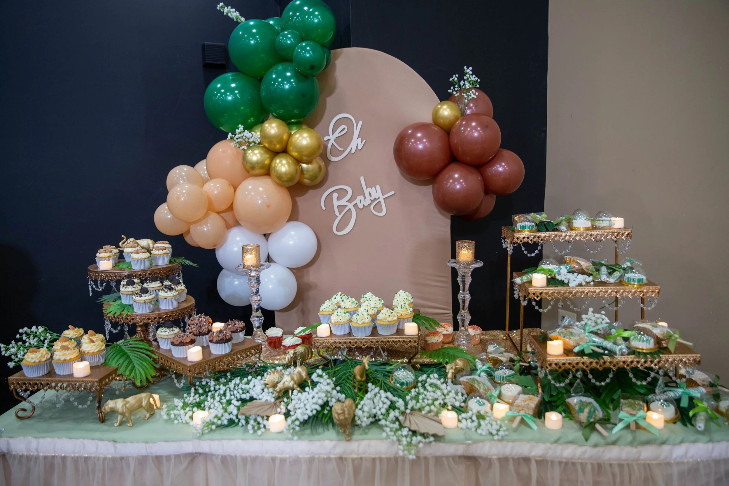 Decorative dessert table with balloons, cupcakes, and festive decorations for a baby shower.