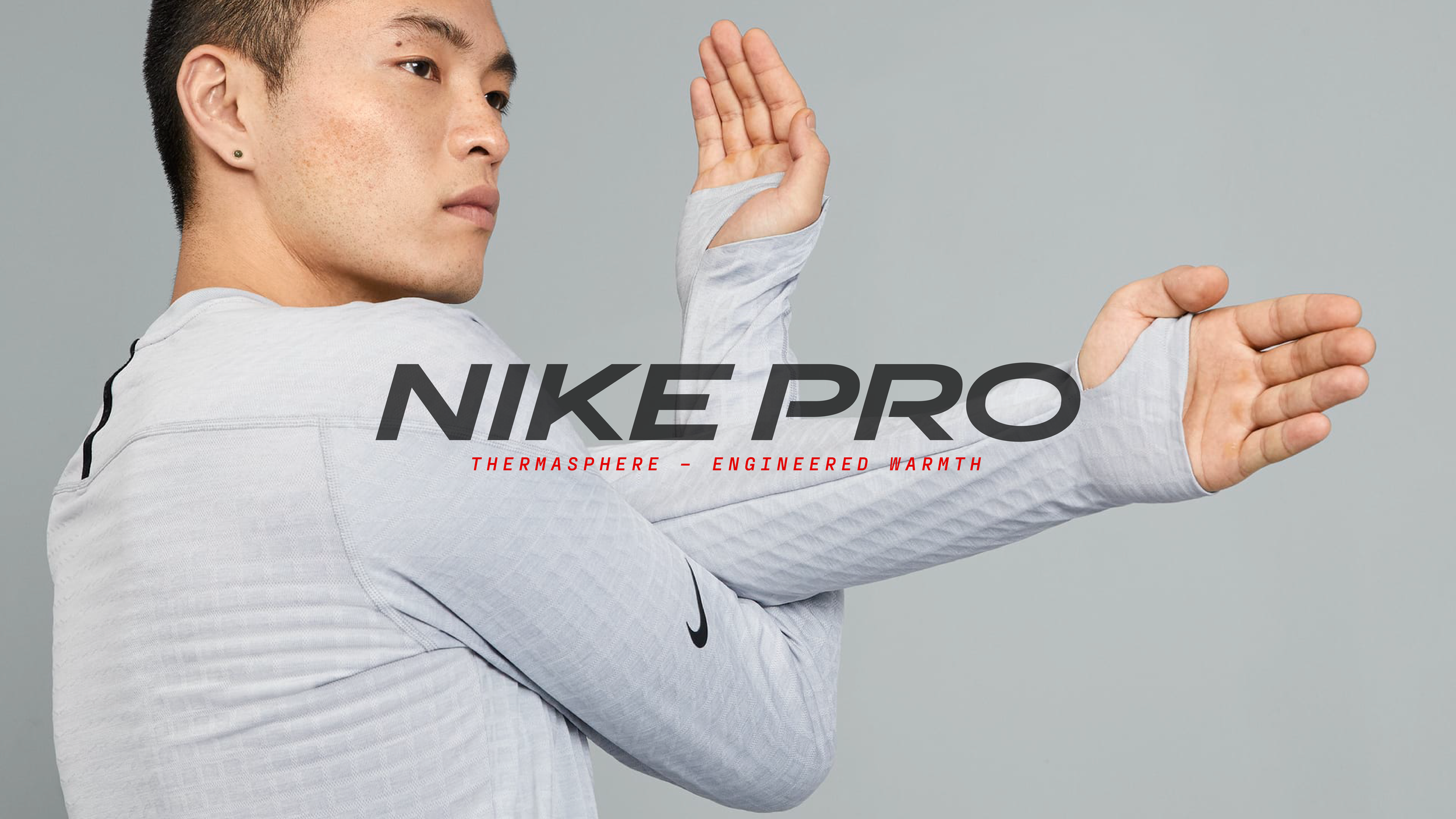 Person wearing Nike Pro Therma-Sphere apparel, with engineered knit for warmth and breathability, extending arm with thumb hole feature.