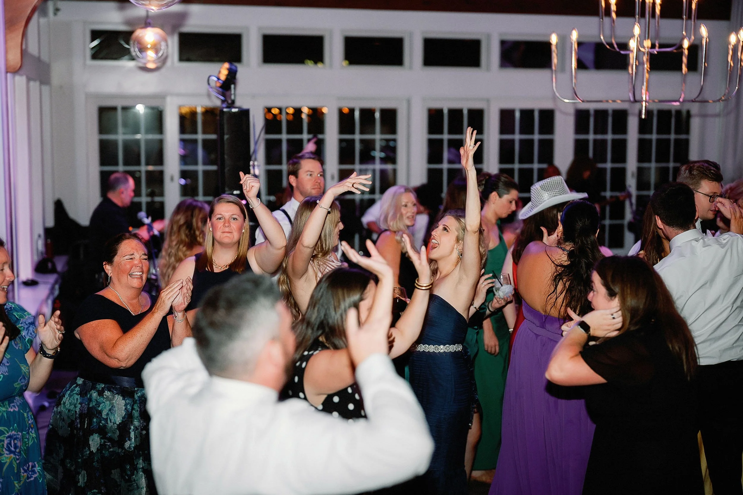 People dancing and celebrating at a party or wedding reception in a decorated indoor venue.
