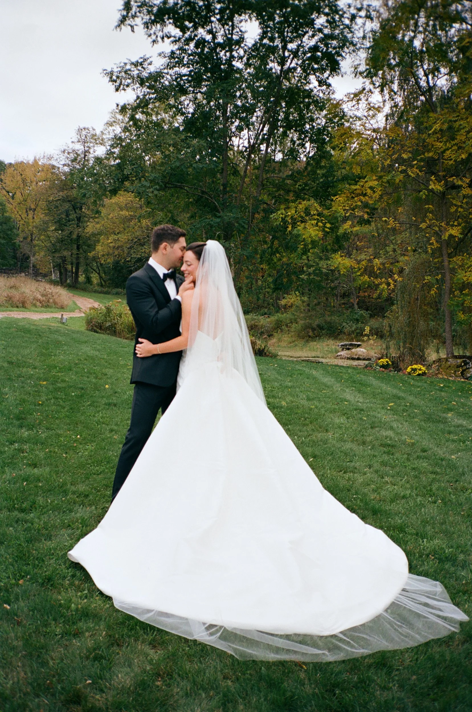 A bride and groom touching foreheads in an outdoor wedding setting.