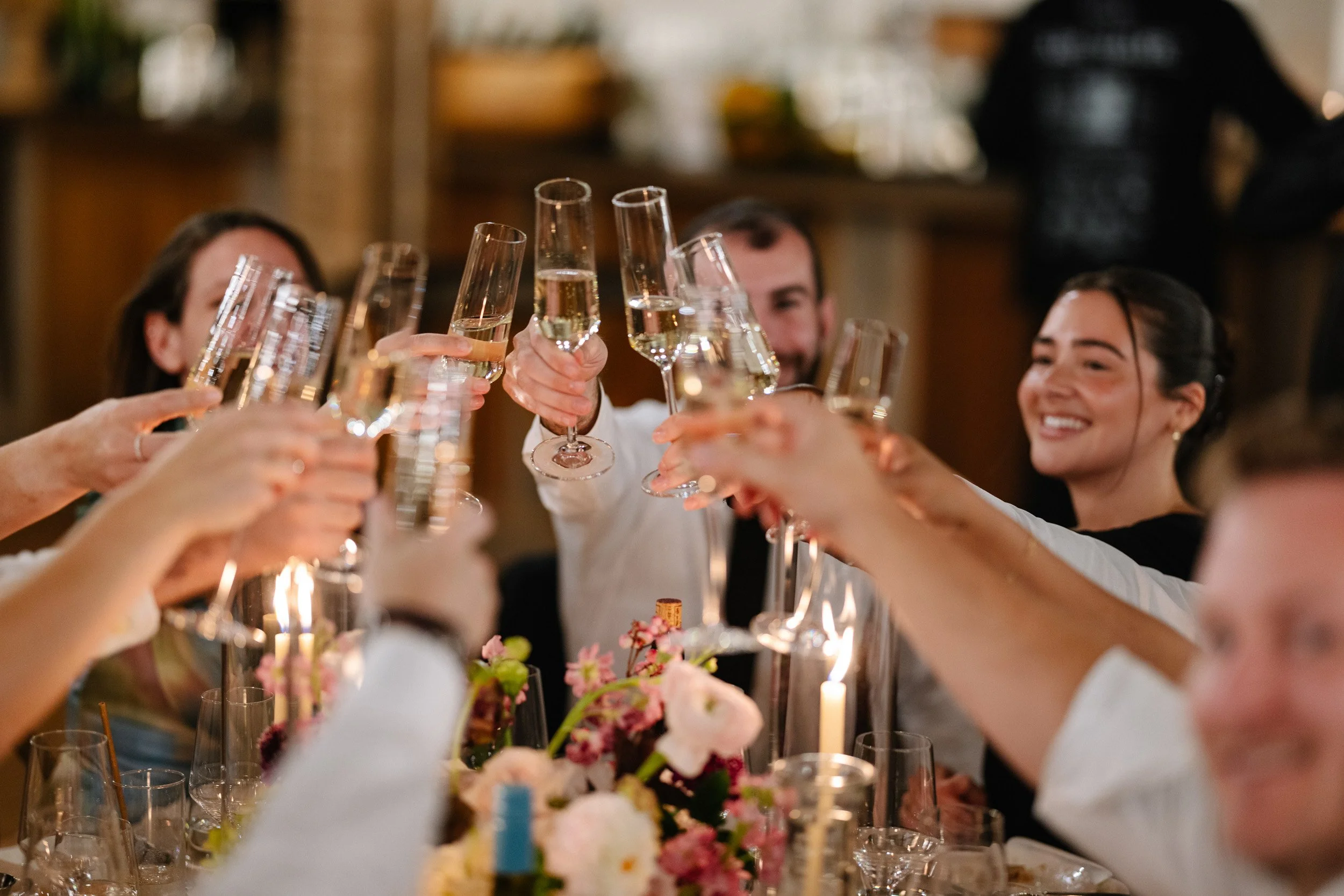 People raising glasses of champagne in celebration at a dinner party.