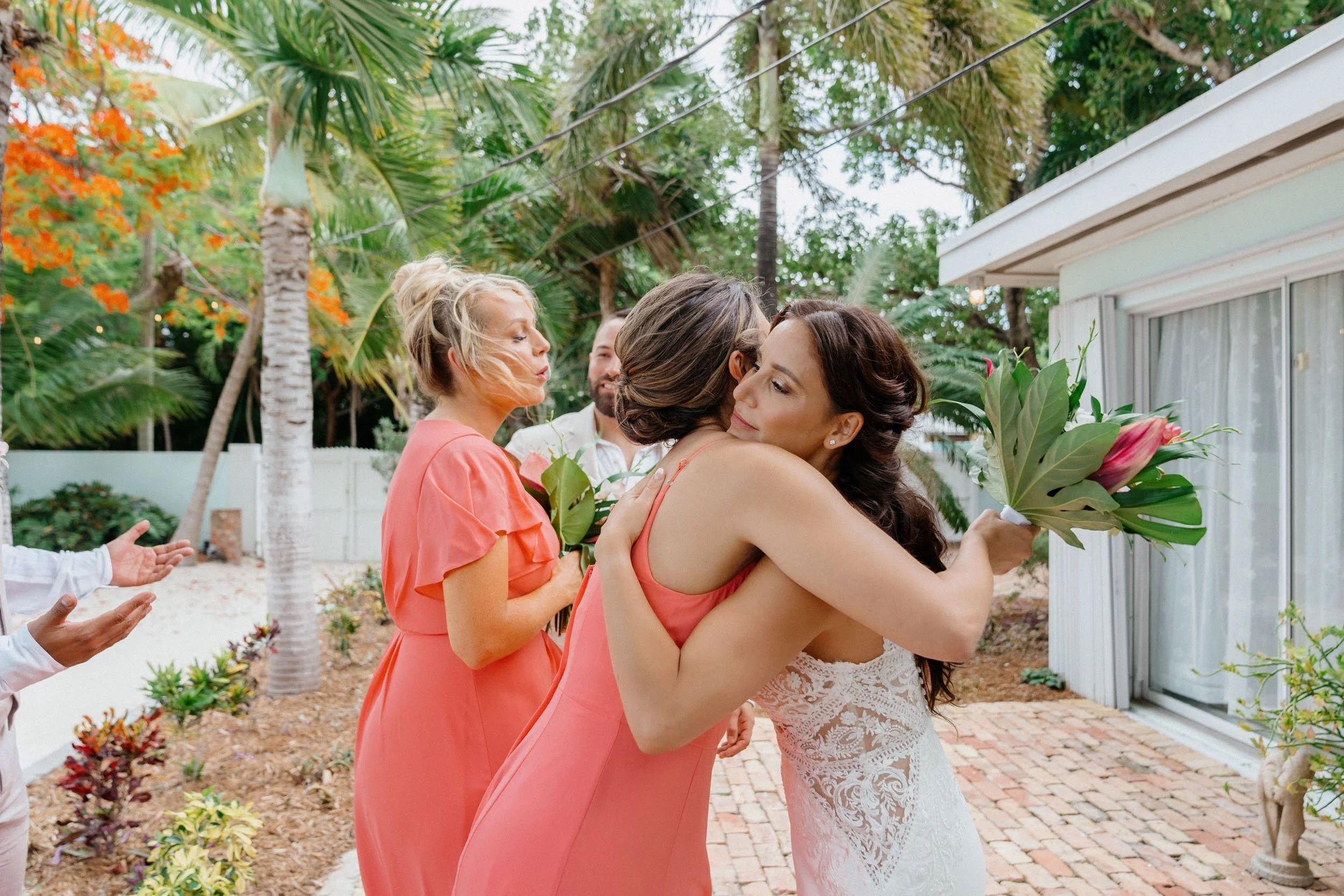 Bridal hug during wedding ceremony outdoors with tropical trees in the background.
