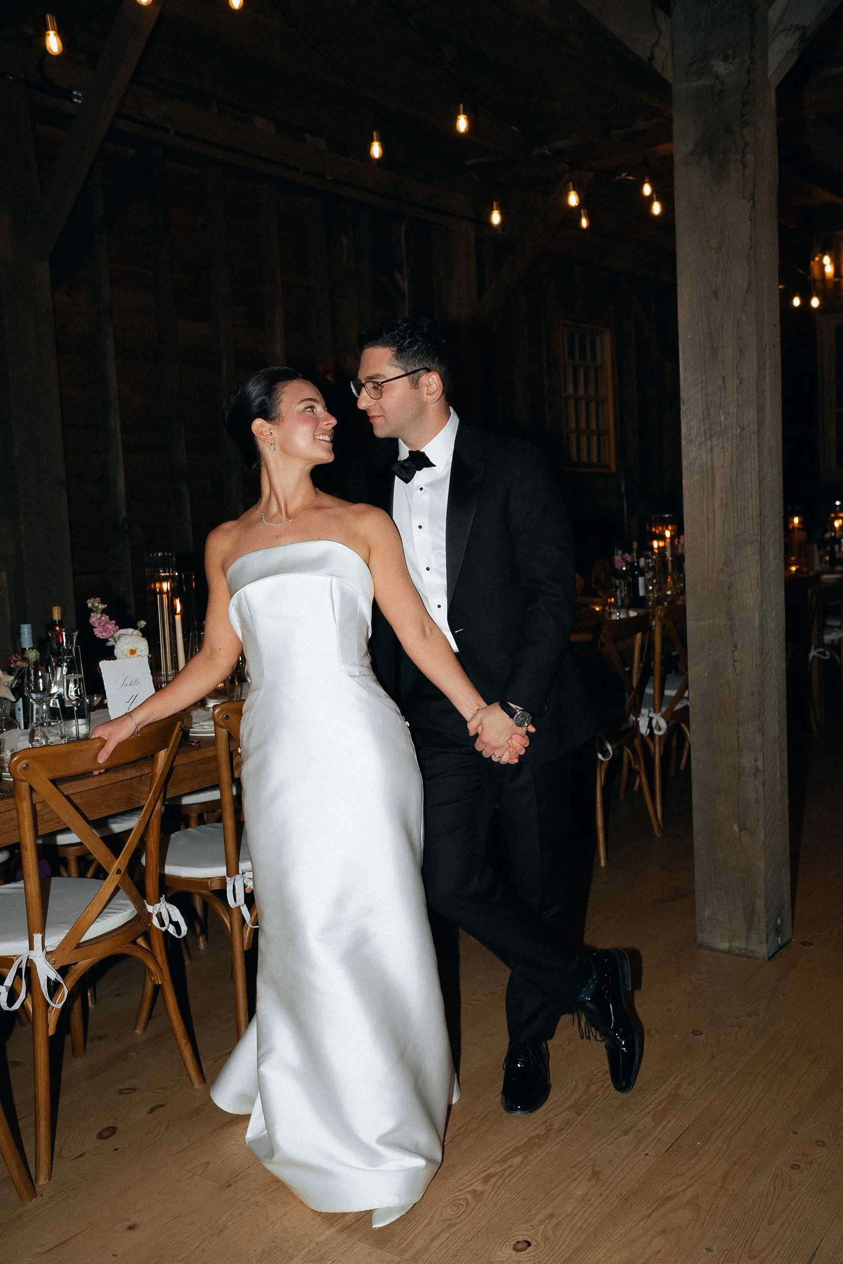 A bride and groom dancing at their wedding reception in a rustic, dimly lit venue.