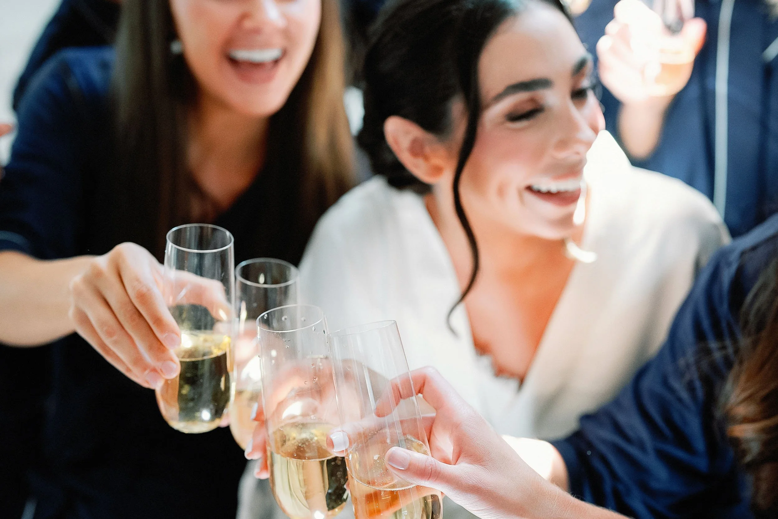 Group of women celebrating, clinking champagne glasses and smiling.