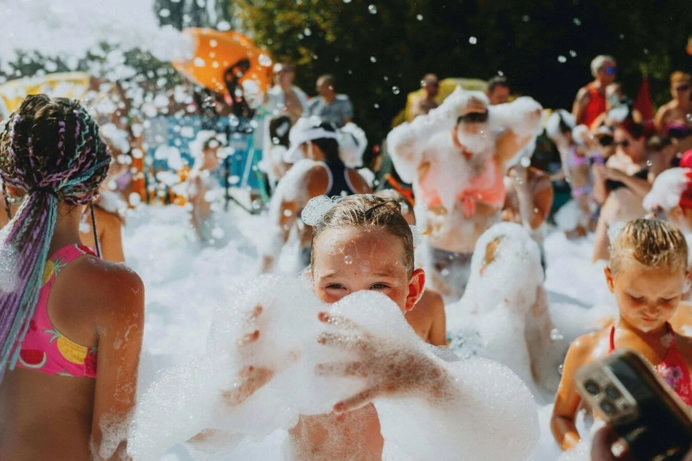 Smiling boy peeking through foam on a bright summer day, capturing classic block party fun