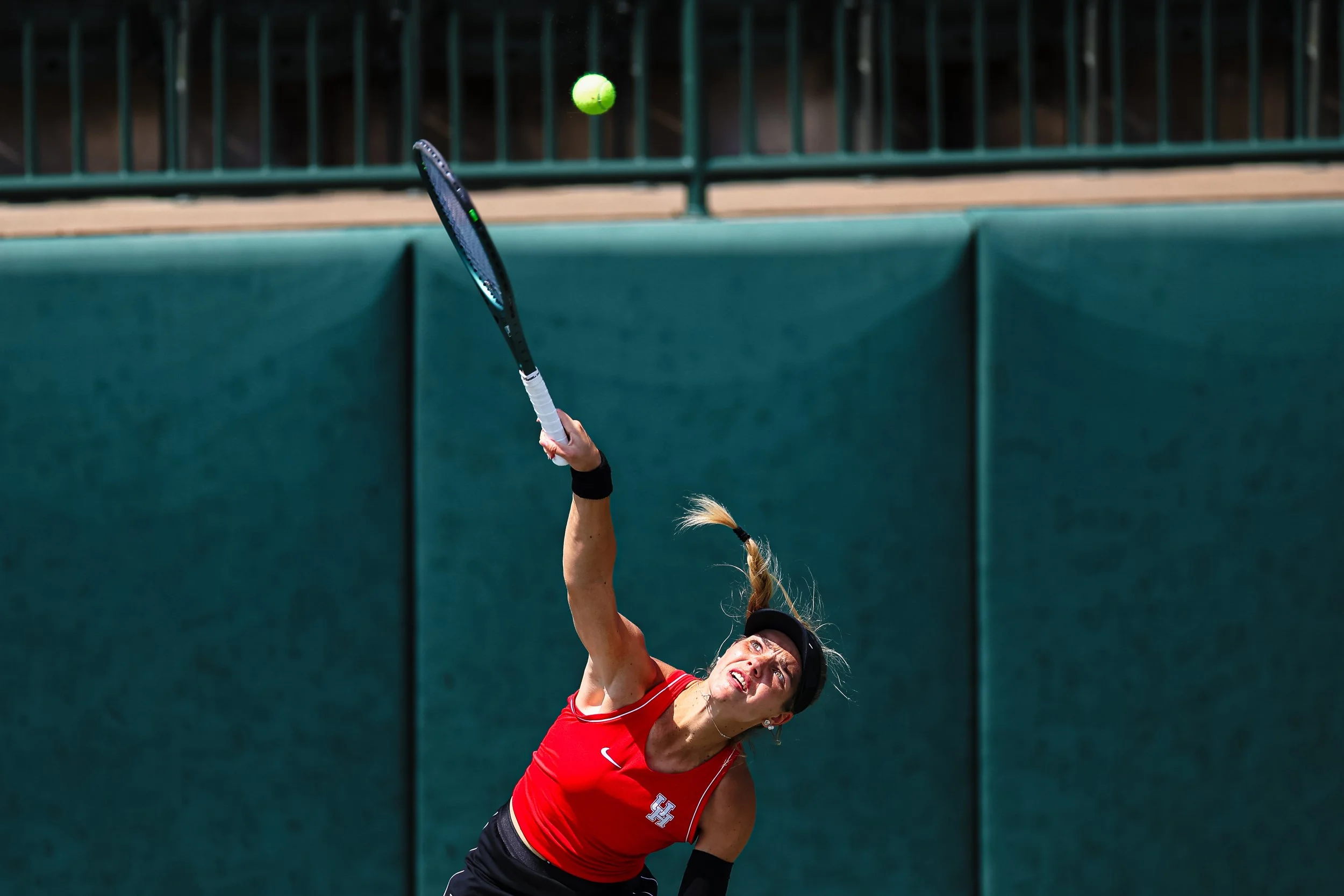 Tennis player in red shirt hitting a tennis ball with a racket.